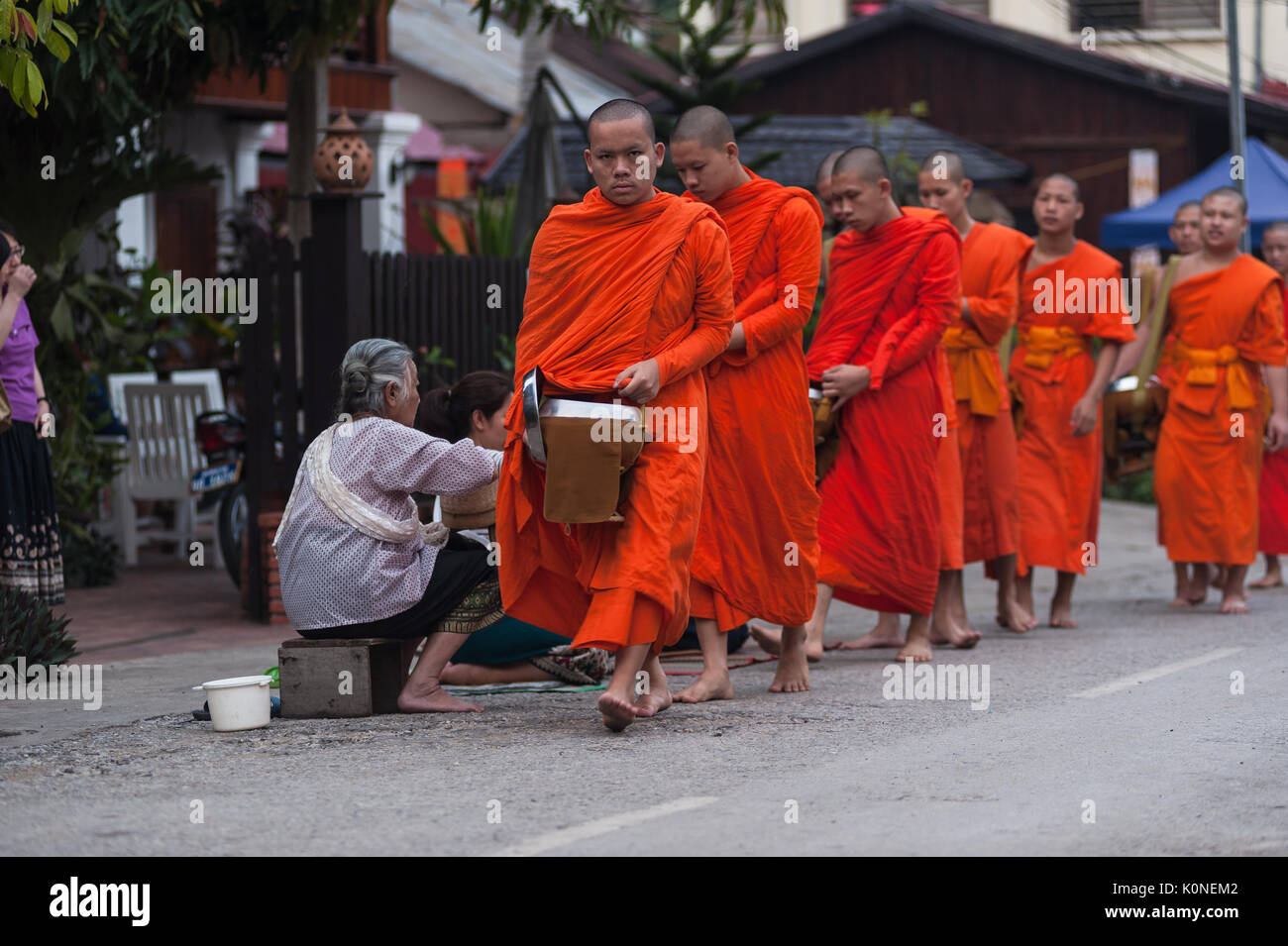 The lay people of Luang Prabang, Laos, engage in the everyday morning Tak Bat ceremony, which exemplifies the traditional bond between monks and monas Stock Photo