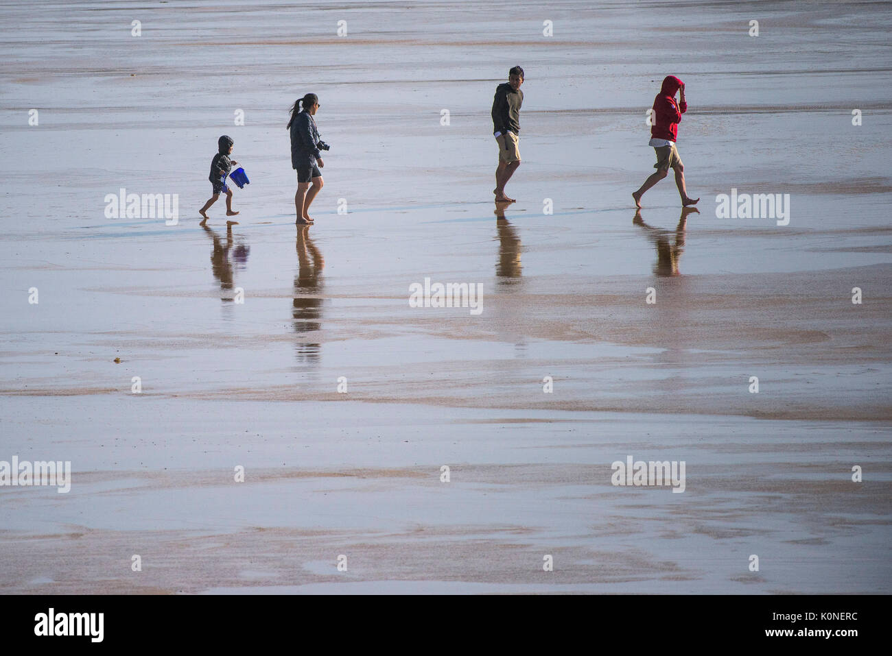 Holidaymakers walking on a beach at low tide. Stock Photo