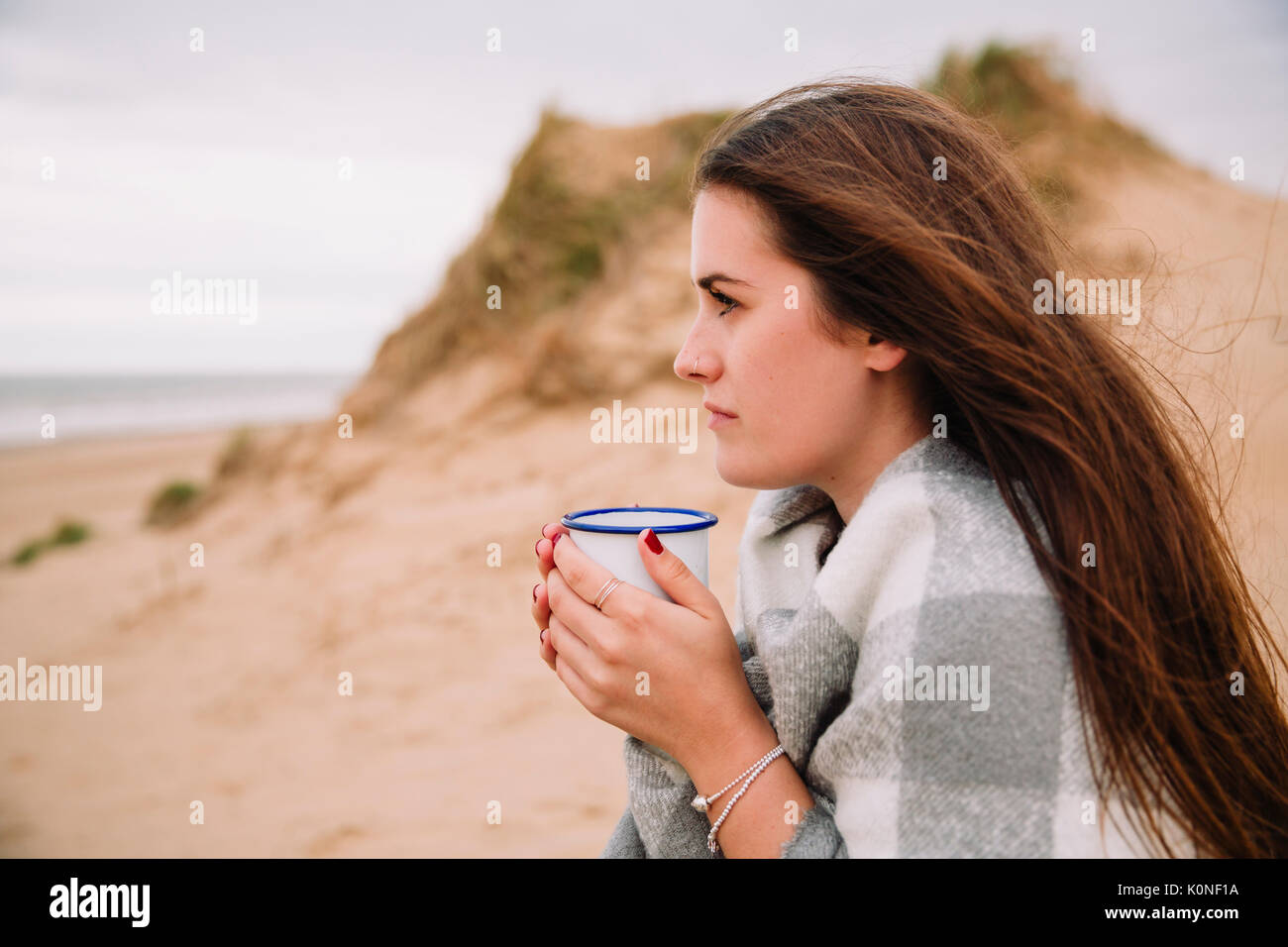 Young woman with cup of hot chocolate on the beach Stock Photo