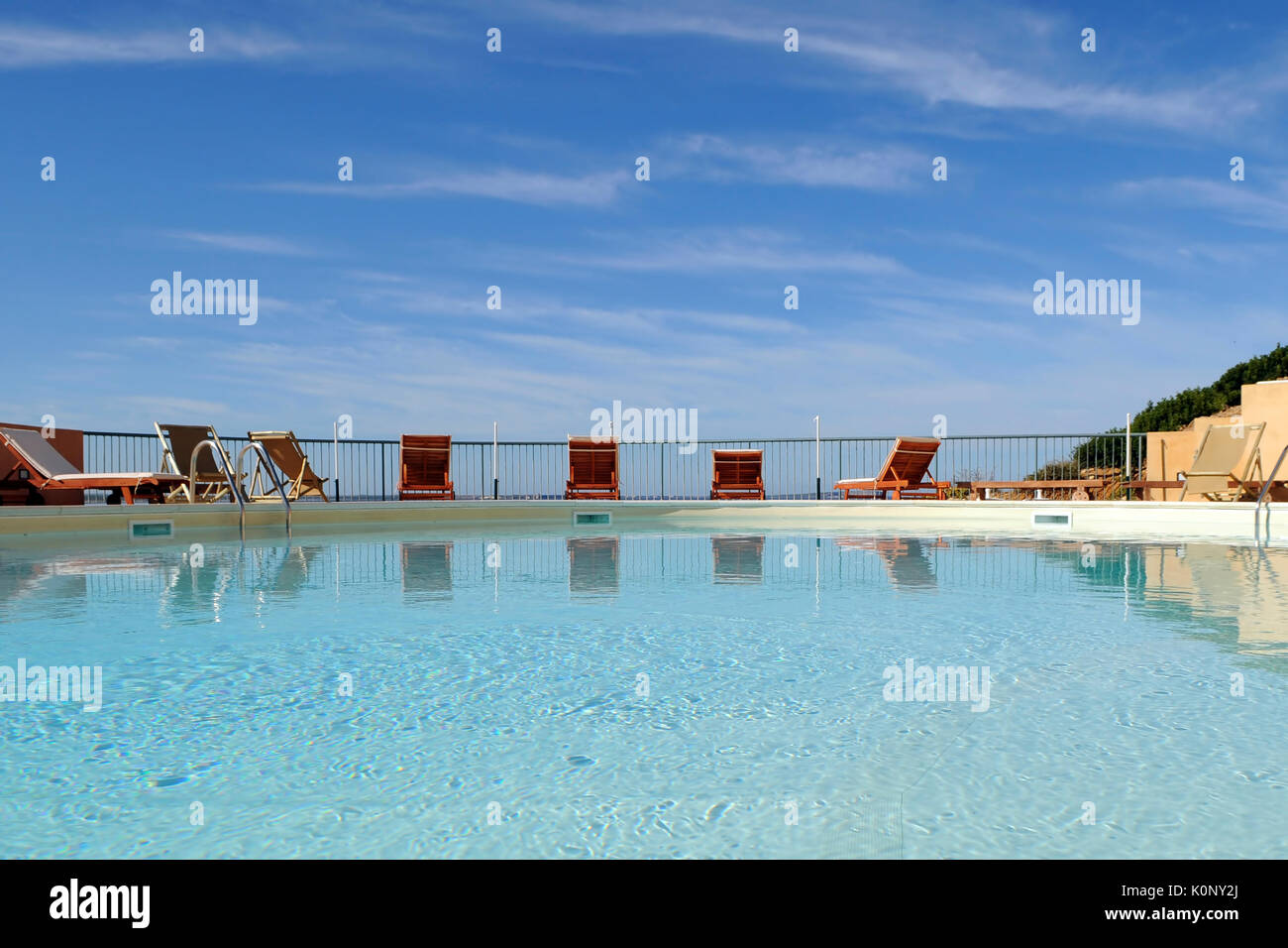 A horizontal image of an outdoor swimming pool with a line of chairs at ...