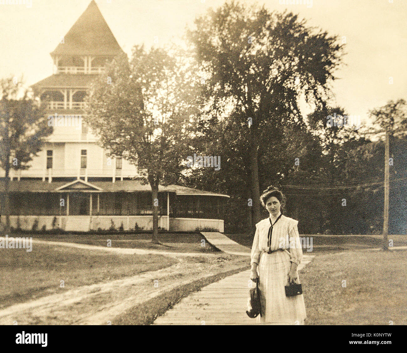 A woman standing in front of the Lake Park Hotel at Lake Minnetonka Minnesota in the year 1907 holding a camera and a handbag Stock Photo