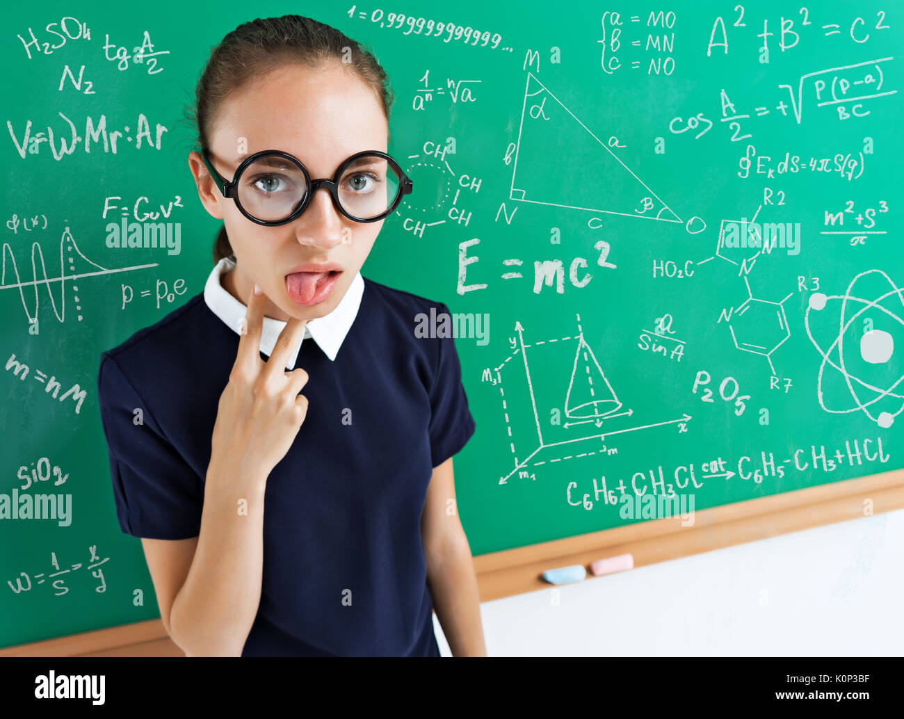 Unhappy student with the examples on the blackboard. Photo of young student in uniform, education concept. Stock Photo