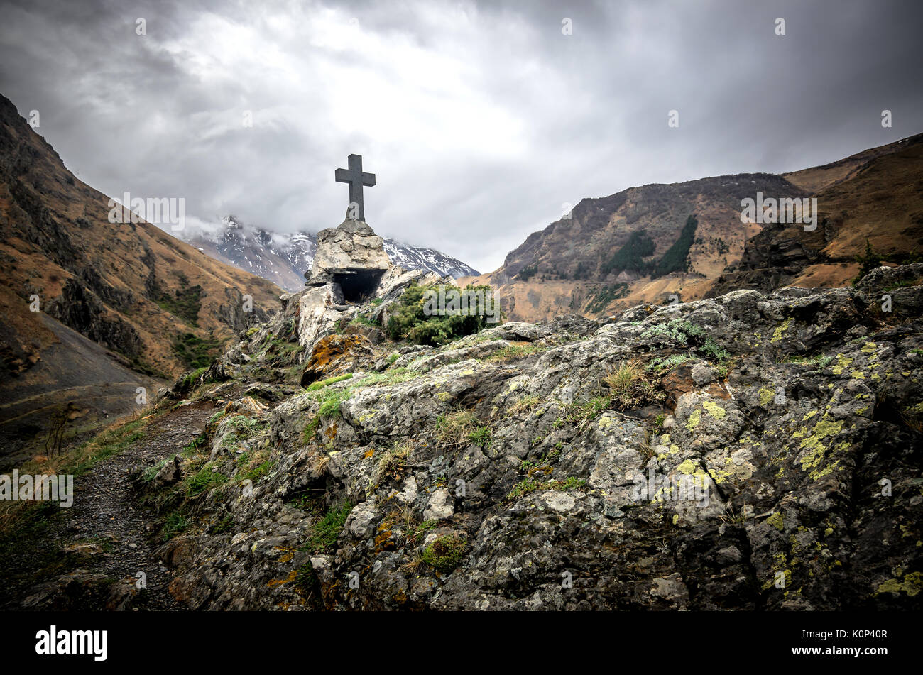 Beautiful view on impressive gorge in Caucasus mountains. Monument in form of Cross and path to it. Stock Photo