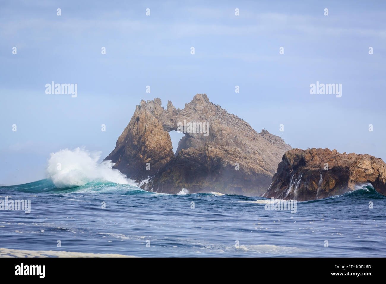 Waves crash on Farallon Islands sea stack with keyhole off coast of San Francisco in the Gulf of Farallon on a sunny, clear day Stock Photo