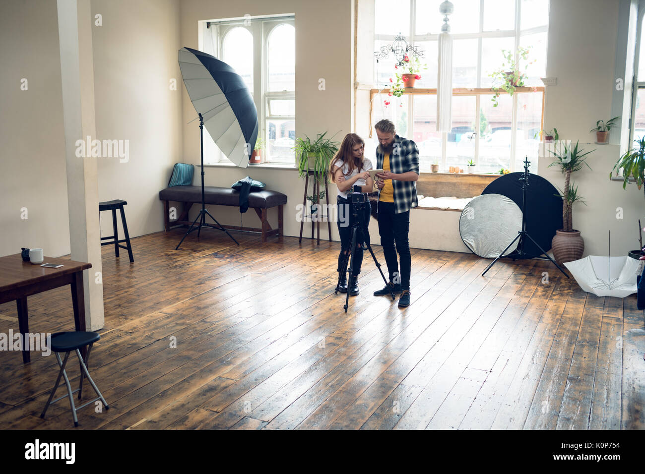 Photographers discussing over digital tablet while standing in studio Stock Photo