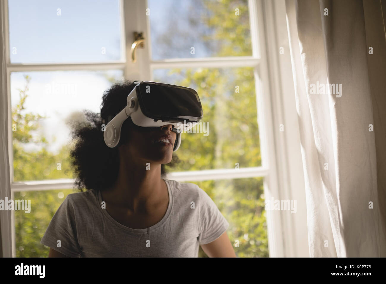 Woman using virtual reality headset at home Stock Photo