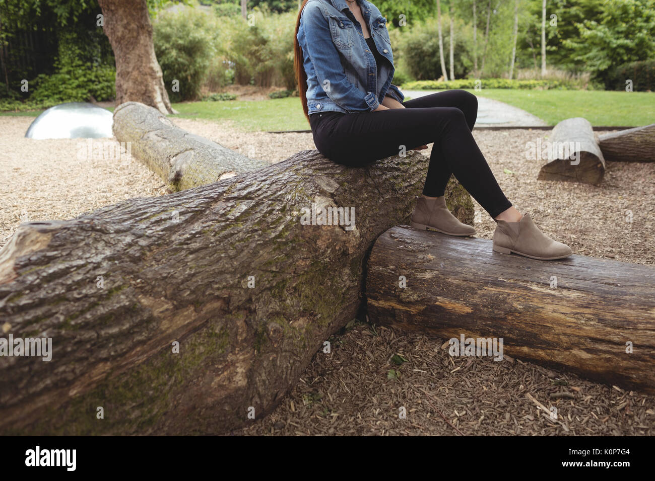 Low section of woman sitting on falle tree at park Stock Photo