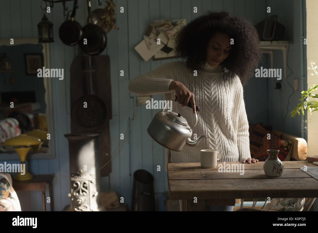 Woman pouring coffee in mug at home Stock Photo