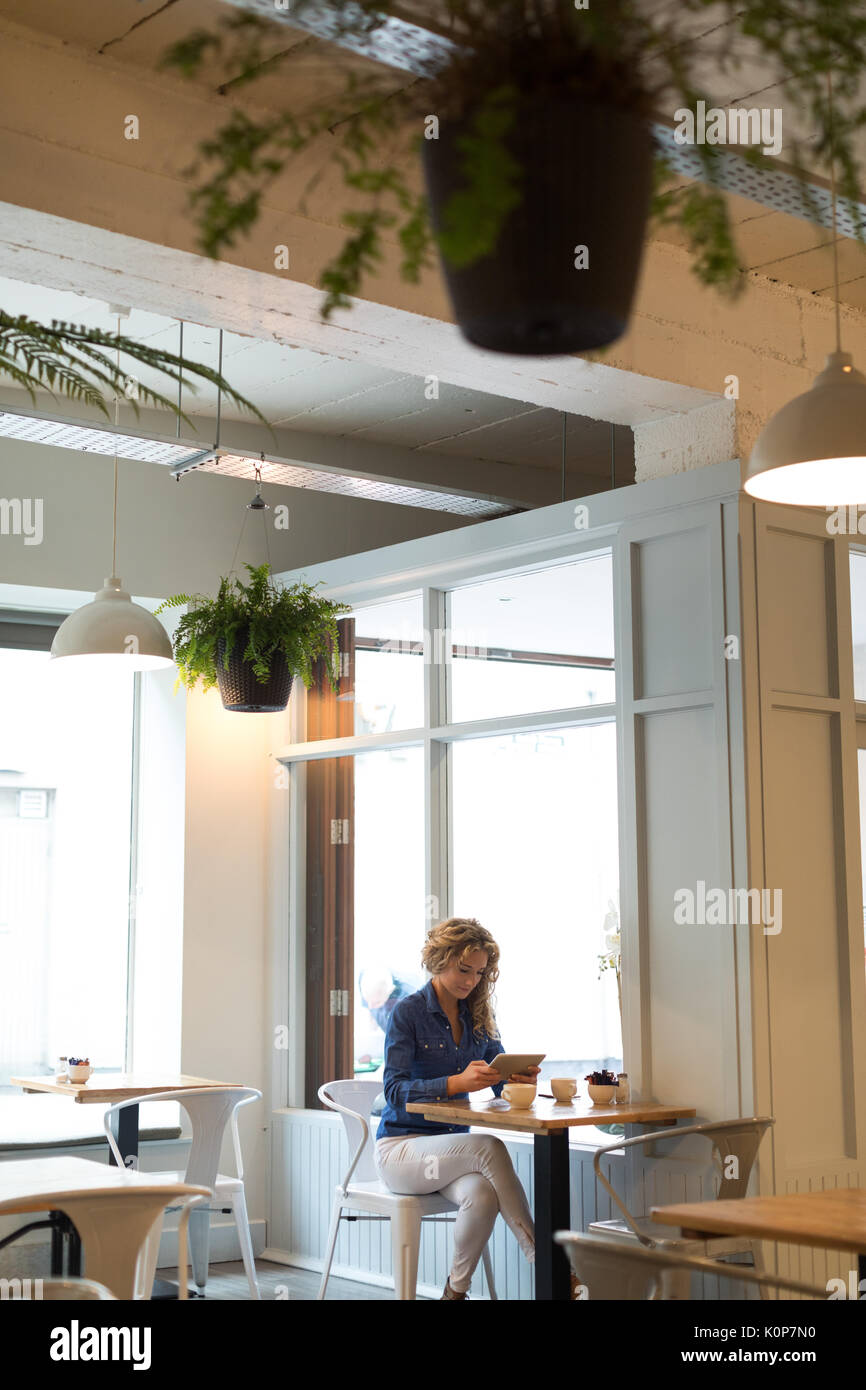 Woman using digital tablet while sitting at table in cafe Stock Photo