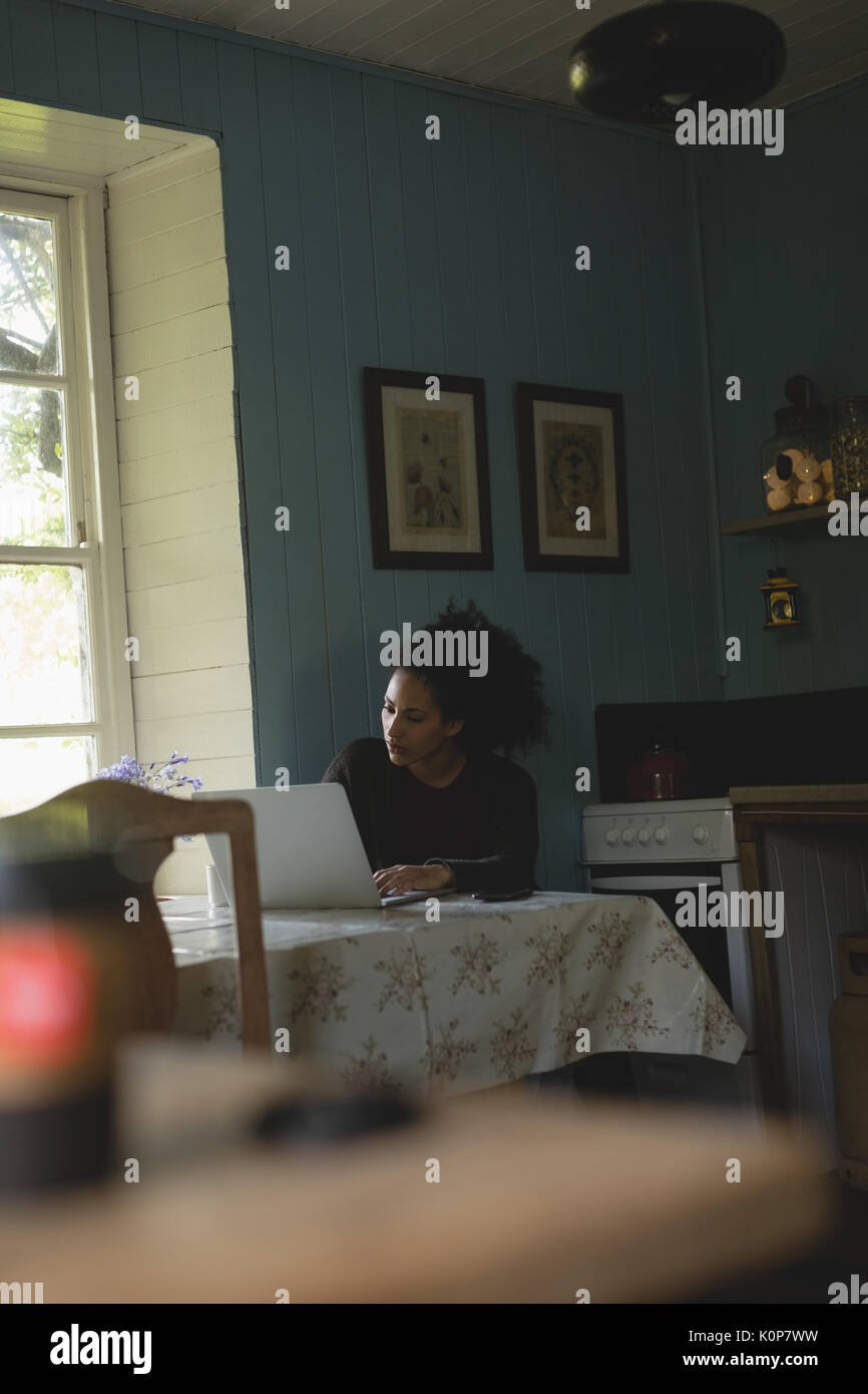 Woman using laptop while sitting on table at home Stock Photo