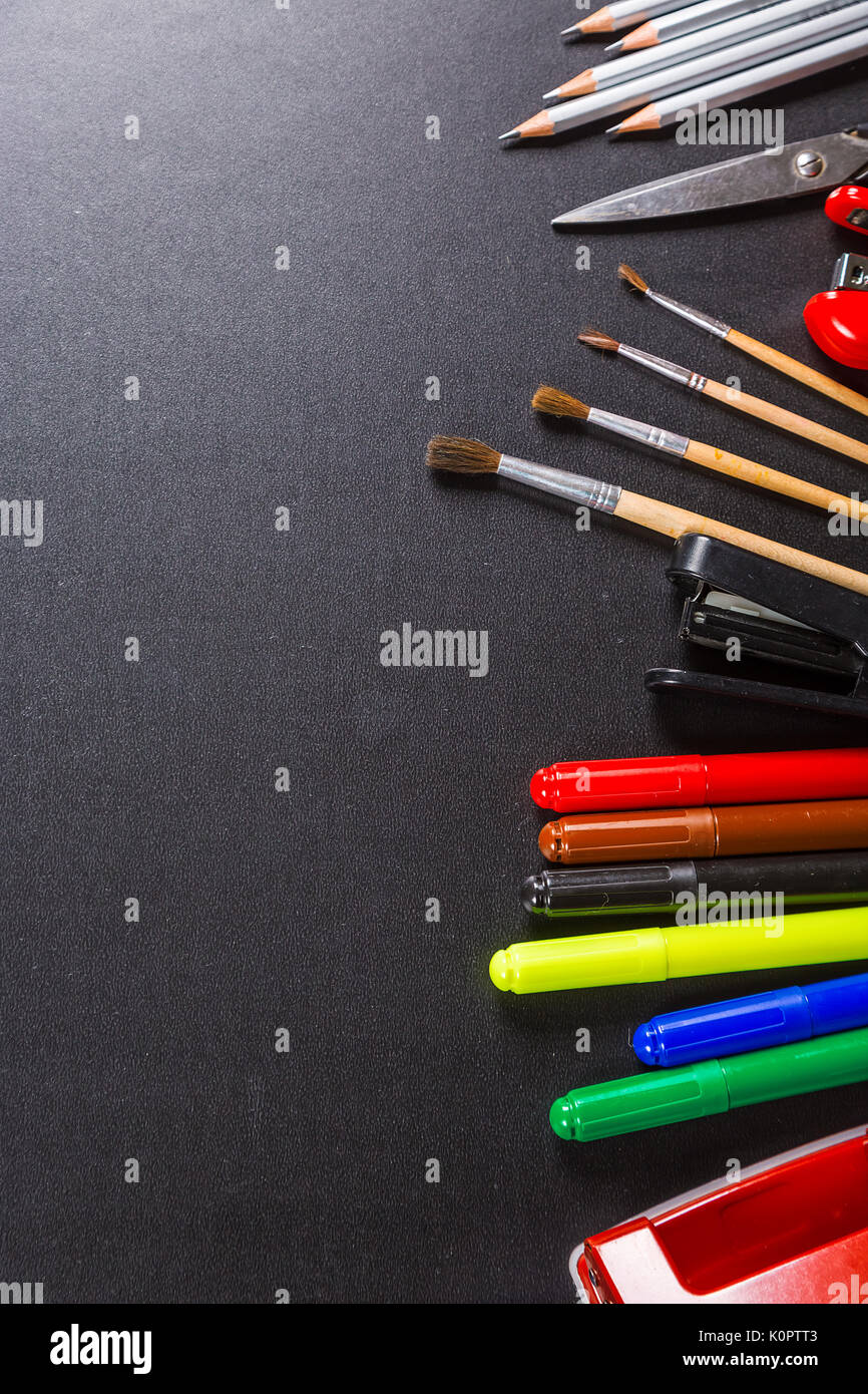 Old blackboard with chalk, stapler, scissors, pencils and stationery. A beautiful backdrop for education, a free space for your text. Back to school. Stock Photo