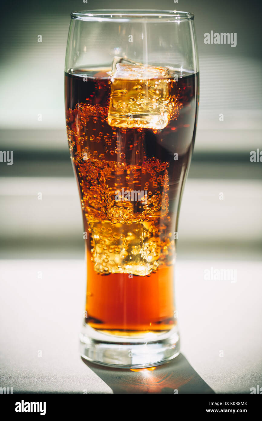 Beautiful cold drink of Cola with ice cubes in a glass on a grey window background with free space Stock Photo