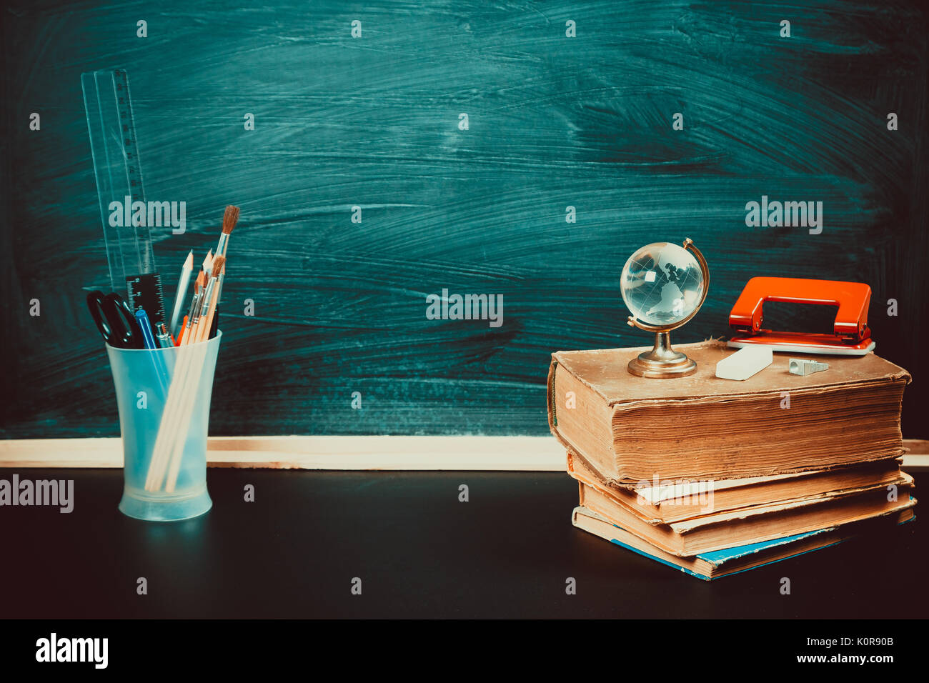 Old blackboard with chalk, books, a globe and a pencil. A beautiful backdrop for education, a