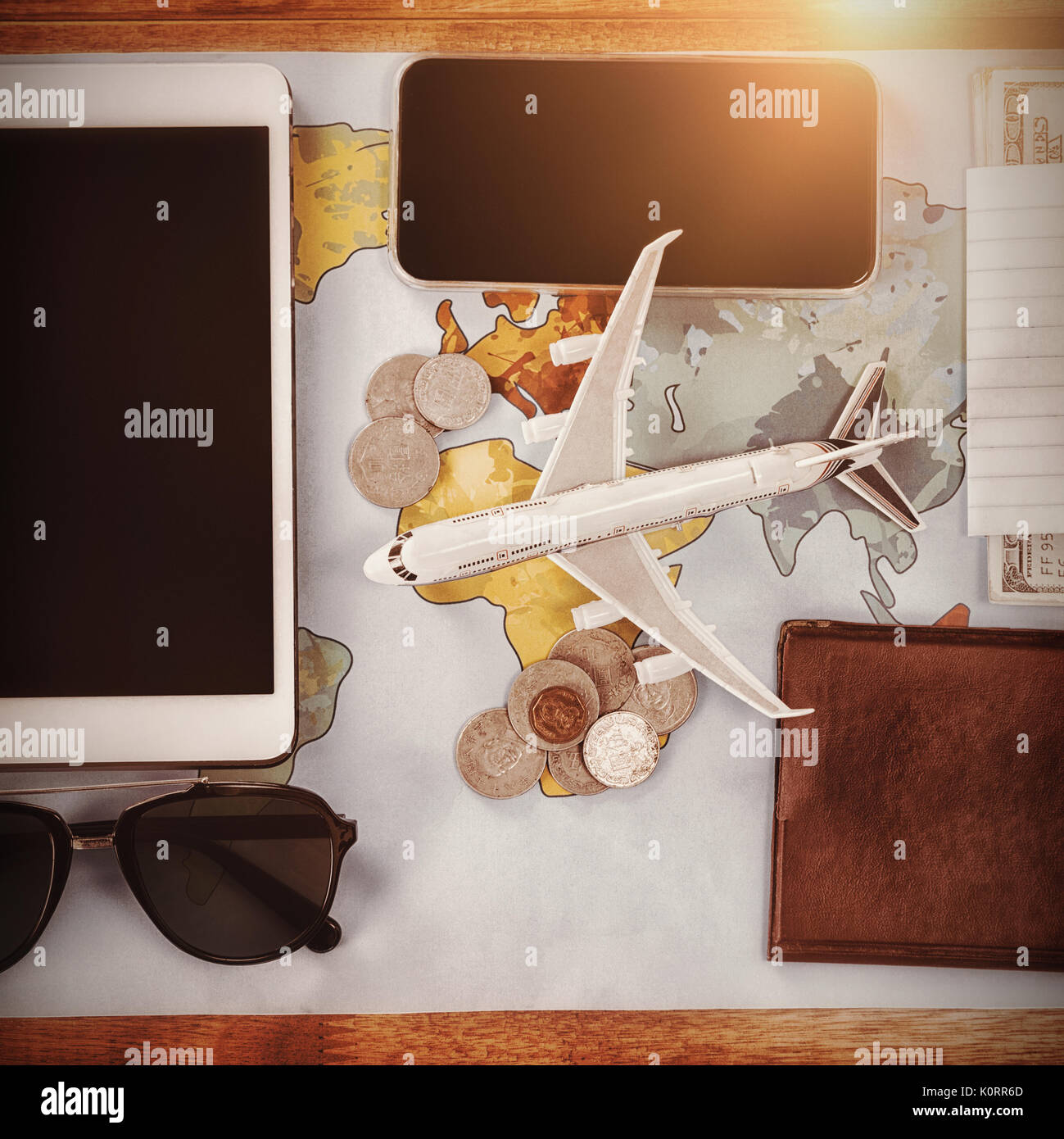 Overhead view of toy airplane by passport and currency with technologies on map at table Stock Photo