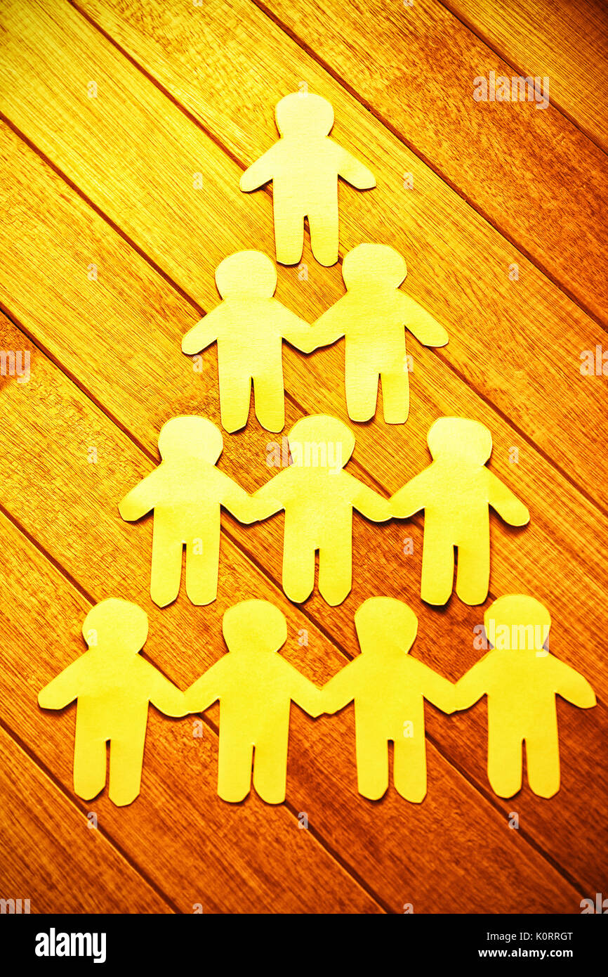 High angle view of paper cut out figures forming human pyramid on table Stock Photo