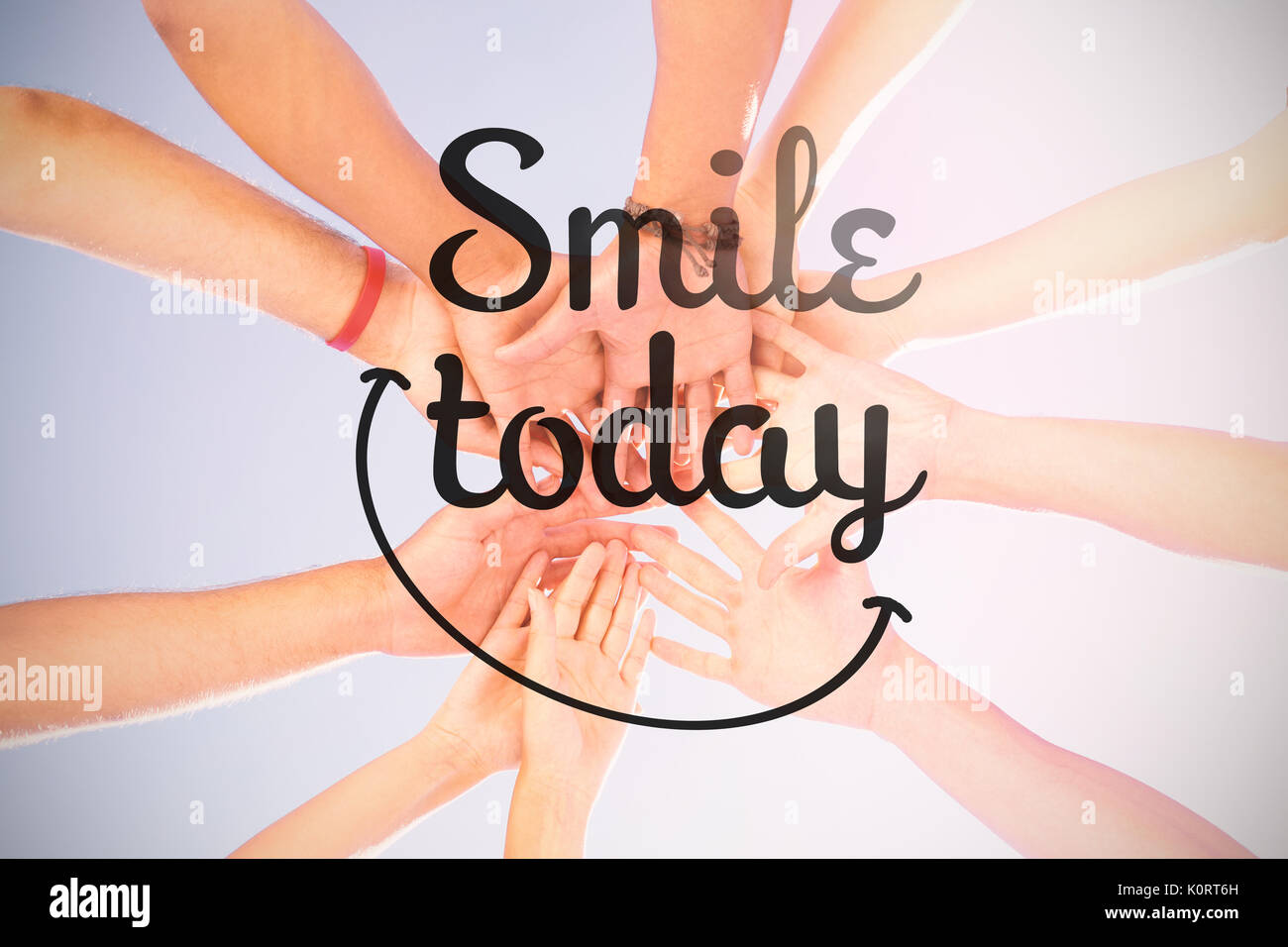 Digital composite image of smile today text against directly below shot of friends stacking hands Stock Photo