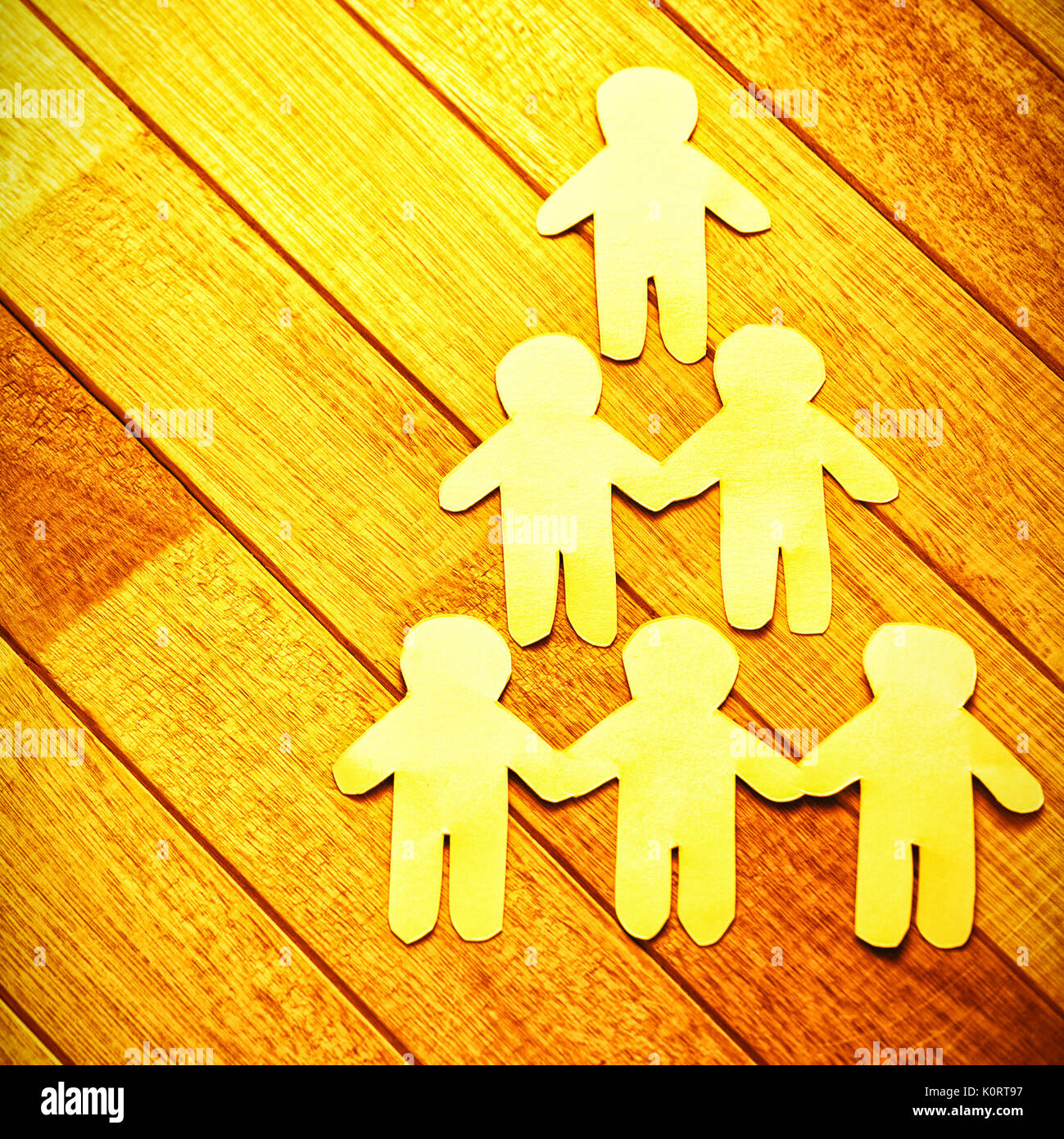 High angle view of paper cut out figures forming human pyramid on wooden table Stock Photo