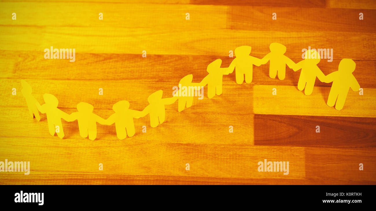 High angle view of yellow paper cutout human chain on wooden table Stock Photo