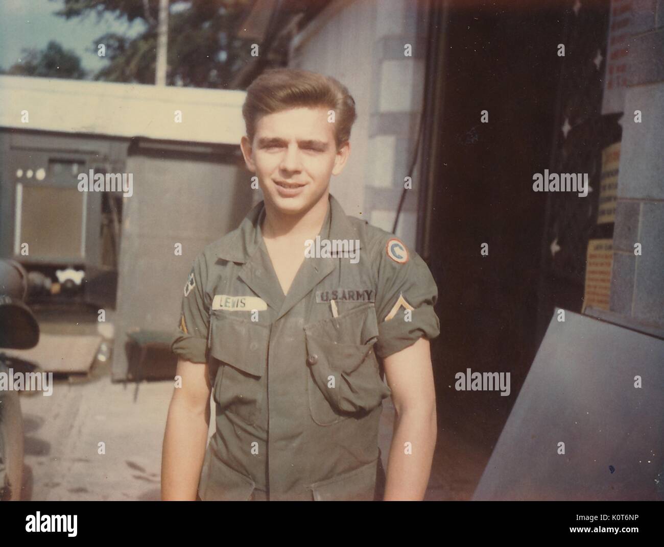 A United States Army Serviceman is posing for a photograph outside of a building, his cuffed sleeves are partially covering his rank insignia, Vietnam, 1968. Stock Photo