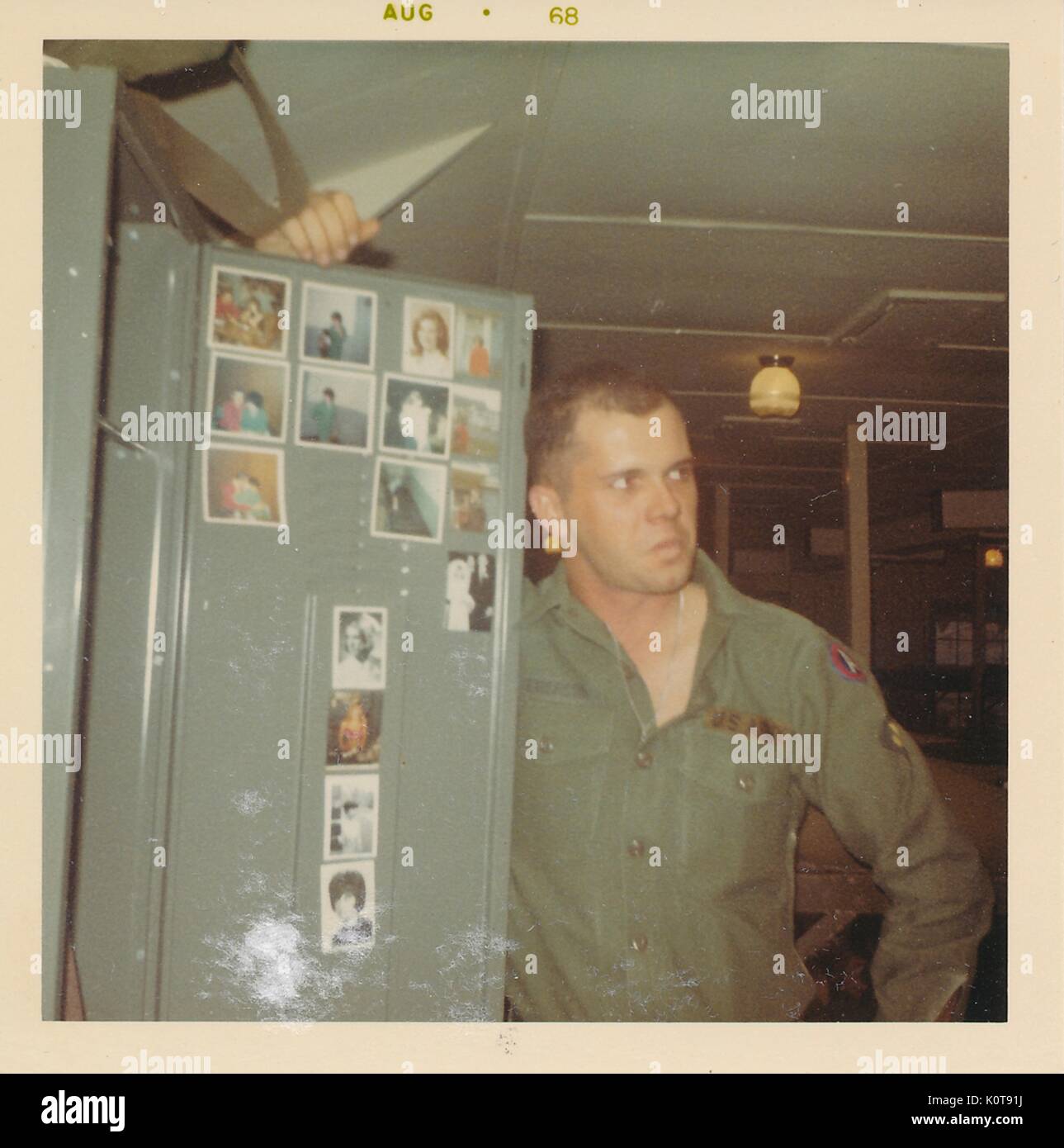 A United States soldier holds open the door to his locker to display his collection of personal photographs, Vietnam, 1968. Stock Photo