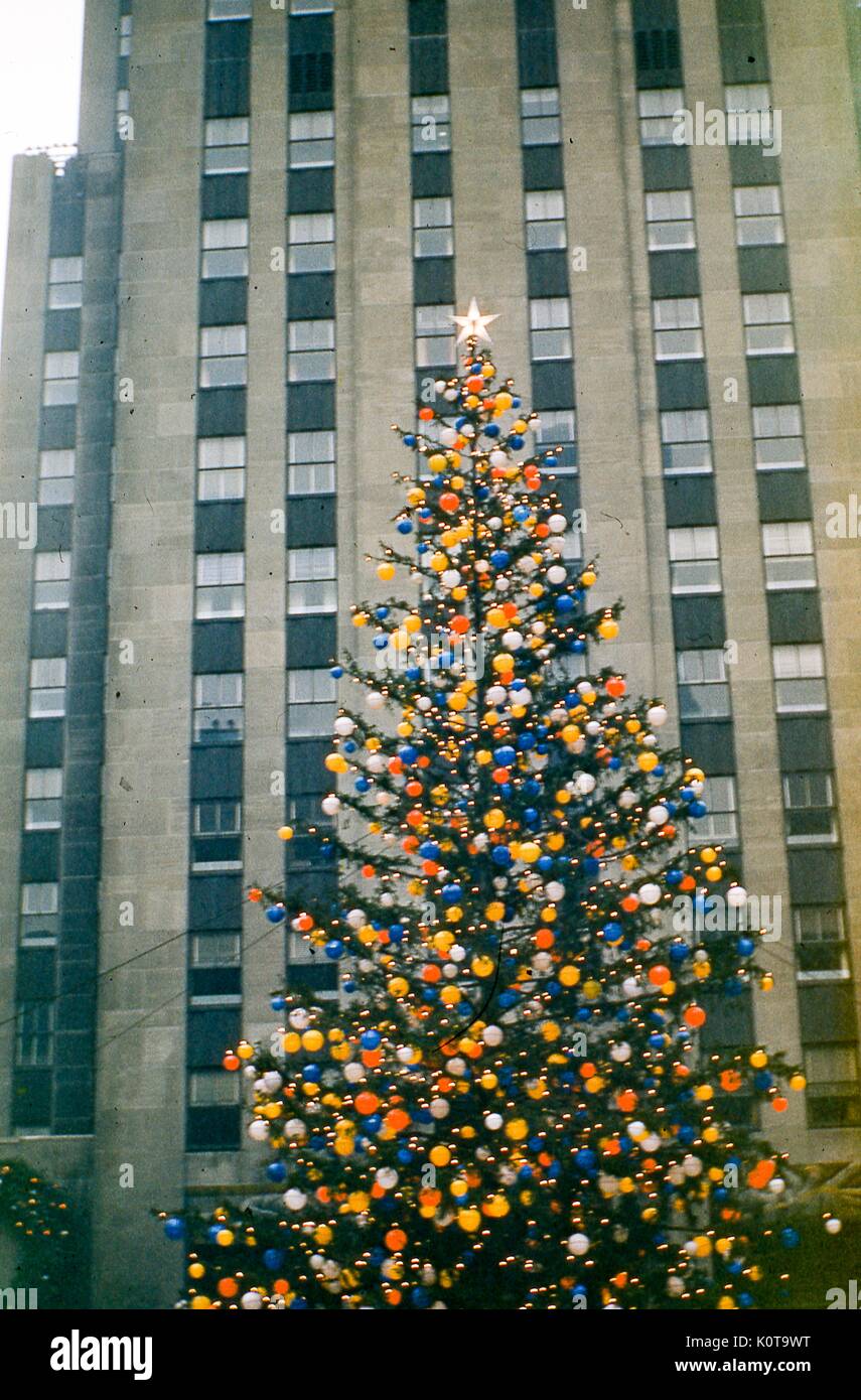 View of the Rockefeller Center Christmas tree fully adorned in colored globe lights and a 5-pointed star, in Rockefeller Center Plaza, midtown Manhattan, New York City, December, 1955. Stock Photo