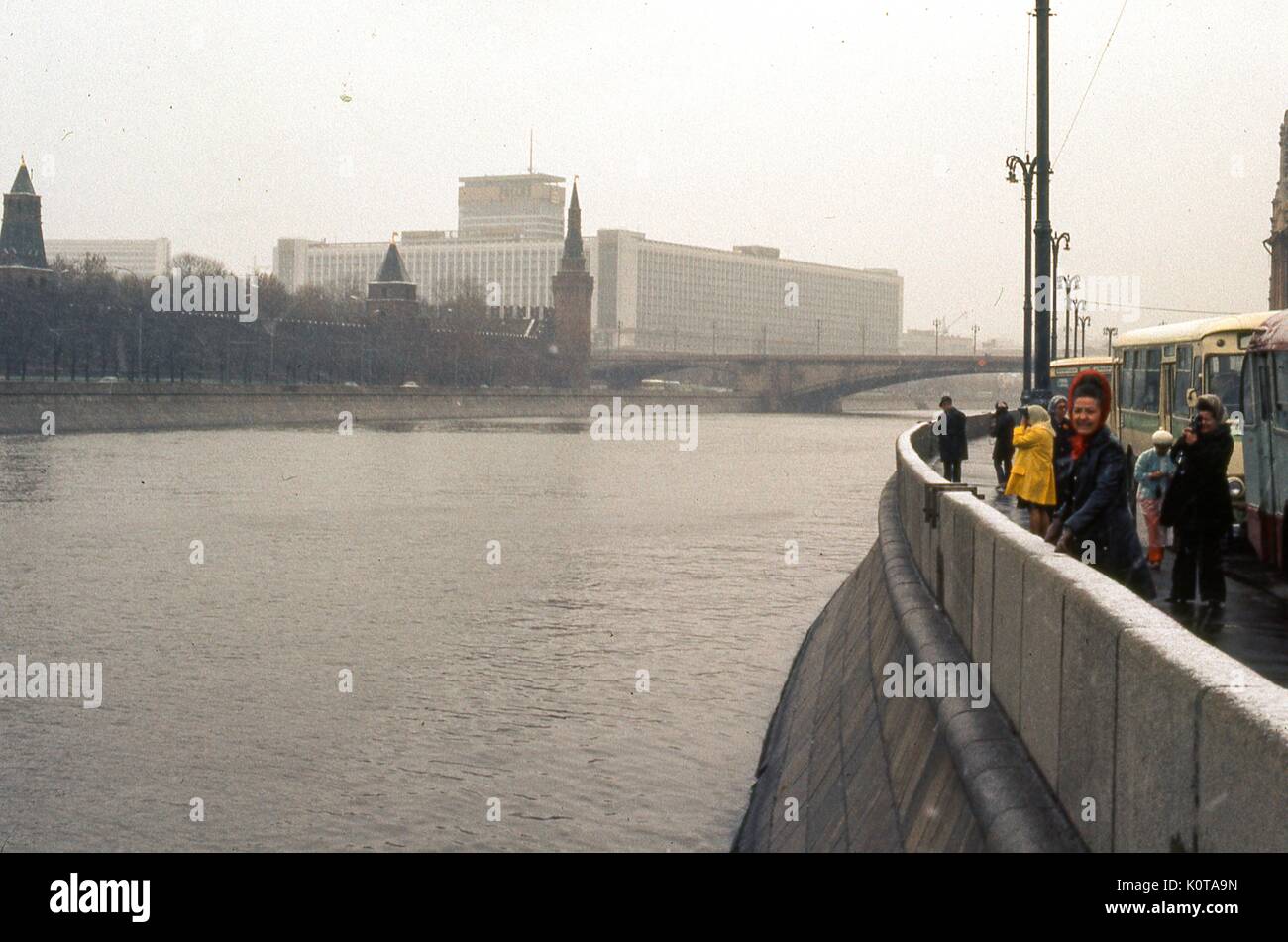 View facing east of the Rossiya Hotel, from the Sofiyskaya embankment in Moscow, Soviet Russia, USSR, November, 1973. At the time, the Rossiya was the largest hotel in the world. At center midground is the Bolshoy Moskvoretsky Bridge spanning the Moscow River due east of the Kremlin. In the right foreground, tourists and cars traverse the roadway next to the sea wall. Along the left side is the outer wall of the Kremlin complex. Stock Photo