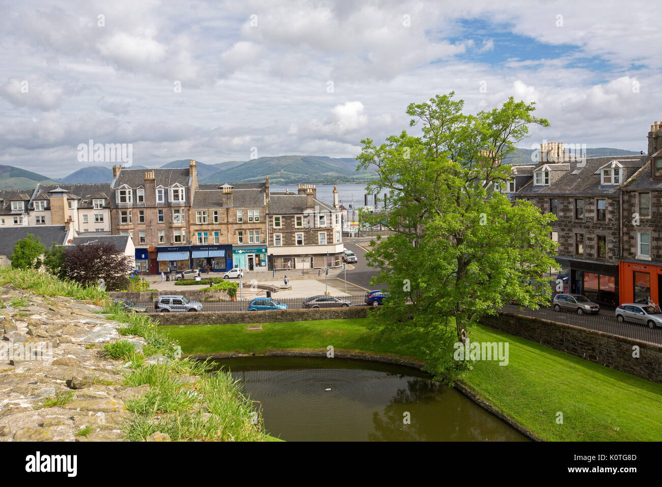 View from historic castle of town of Rothesay on island of Bute, with castle wall & moat in foreground & mountains of Scottish mainland in distance Stock Photo