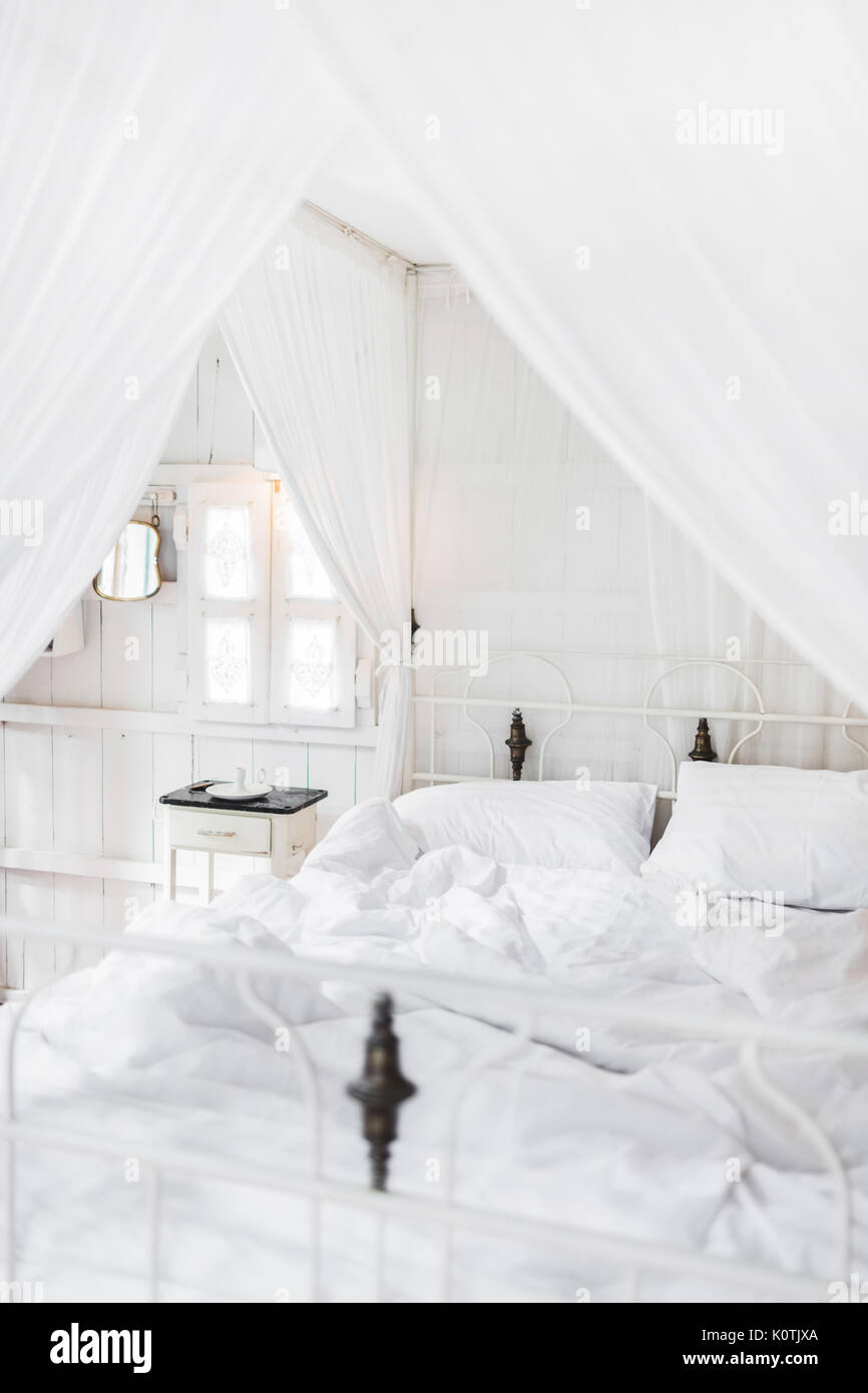 White bed in the morning in light vintage wooden room. Interior in white color Stock Photo