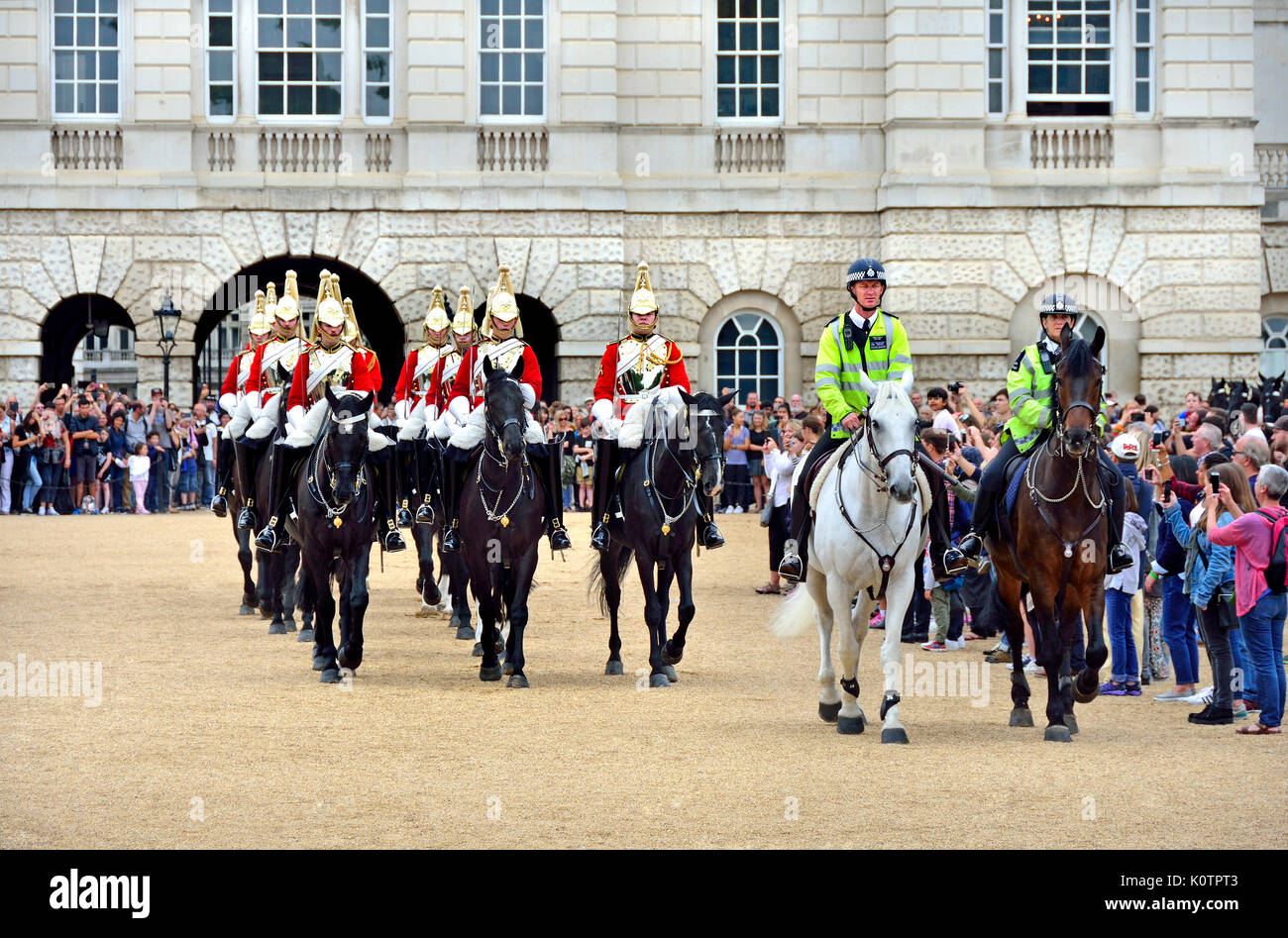London, England, UK. Life Guards, part of the Household Cavalry, changing the guard on Horse Guards Parade, accompanied by mounted police Stock Photo