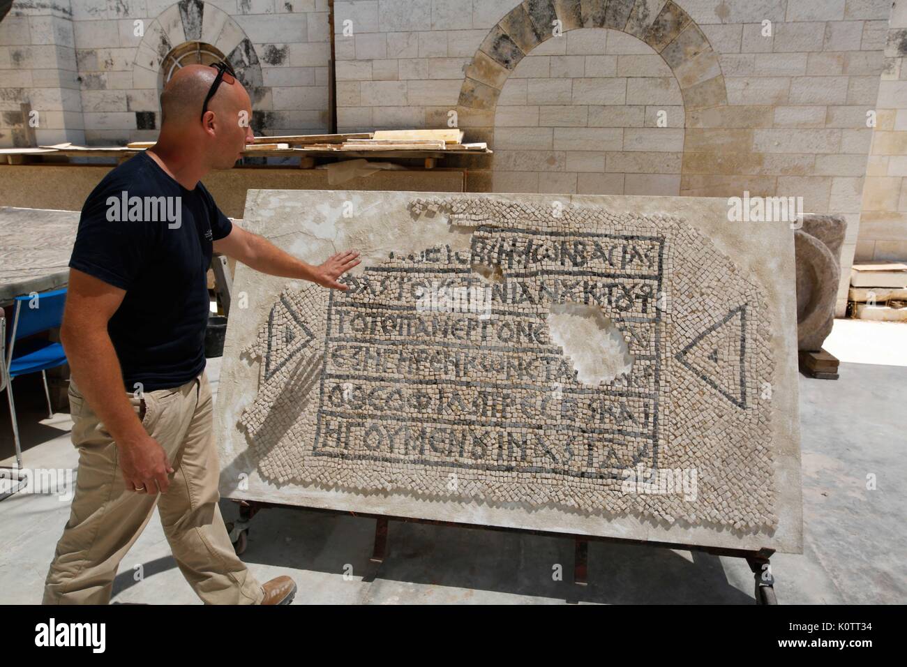 (170823) -- JERUSALEM, Aug. 23, 2017 (Xinhua) -- Israel Antiquities Authority worker Shmulik Frairaich shows and explains a 1,500-year-old mosaic floor at the Israel Antiquities Authority mosaic workshop in the Rockefeller museum in Jerusalem, on Aug. 23, 2017. The Greek inscription mentioning the Byzantine emperor Justinian, was exposed on a mosaic floor in a room that was probably used as a hostel for pilgrims, according to Israel Antiquities Authority. A 1,500-year-old mosaic floor, with a Greek inscription, was discovered this summer following groundwork for Partner communications cable in Stock Photo
