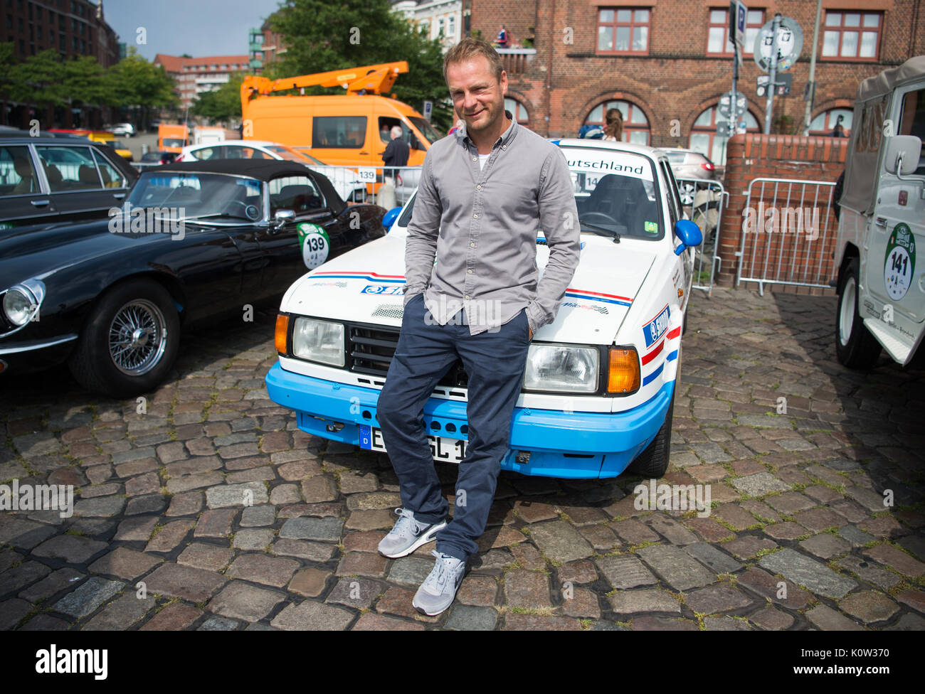 Hamburg, Germany. 24th Aug, 2017. The German actor Hinnerk Schoenemann is standing next to a Skoda 130 RS, built in 1976, at the start of the Hamburg-Berlin Vintage Car Rallye in Hamburg, Germany, 24 August 2017. About 180 vintage cars started the rallye today. Photo: Christophe Gateau/dpa/Alamy Live News Stock Photo