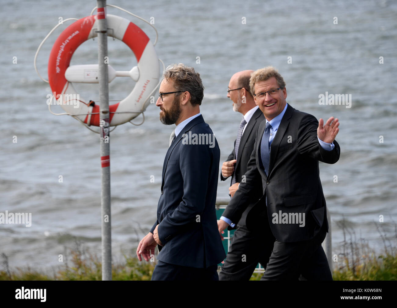 Denmark. 25th August, 2017. The Economy Minister of the state of Schleswig-Holstein, Bernd Buchholz (R), walking with his Danish counterpart Ole Birk Olesen (L) and the deputy project director Ajs Dam to the site of the proposed tunnel in Rødbyhavn, Denmark, 25 August 2017. The topic of the talks was the future Fehmarnbelt tunnel. Photo: Carsten Rehder/dpa/Alamy Live News Stock Photo