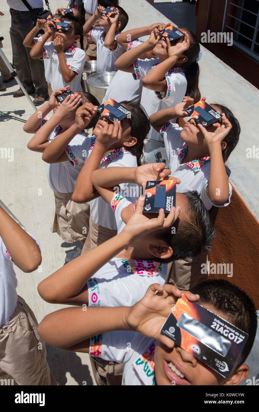 School children use protective glasses to view a partial solar eclipse at an elementary school August 21, 2017 in Aquismon, Mexico. The total eclipse swept across a narrow portion of the contiguous United States from Oregon to South Carolina and a partial solar eclipse was visible across the entire North American continent along with parts of South America, Africa, and Europe. Stock Photo
