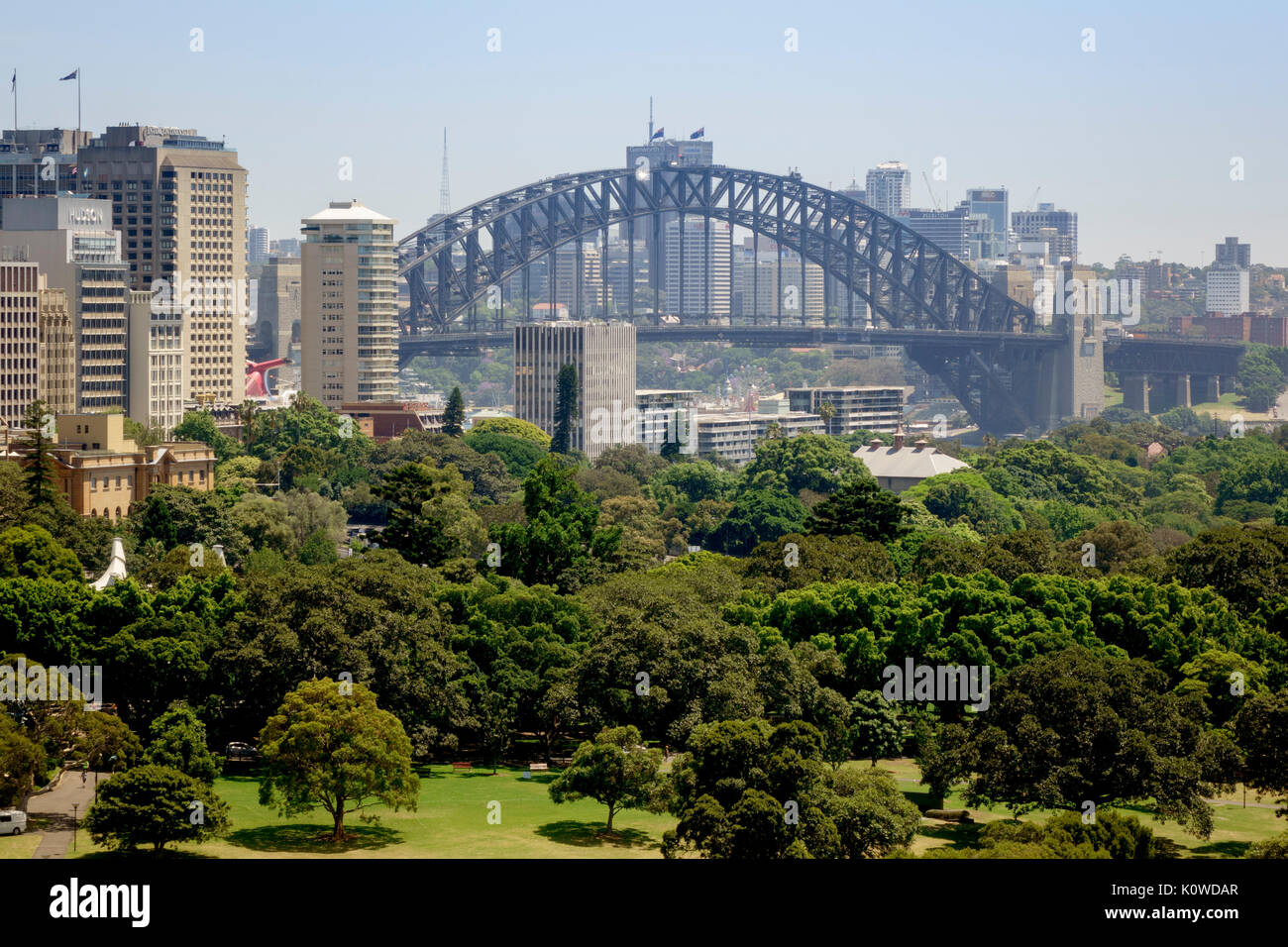 The Sydney Harbour Bridge And The Central Business District Australia The Domain Park Is In The Foreground, People Are Walking On Top Of The Bridge Stock Photo