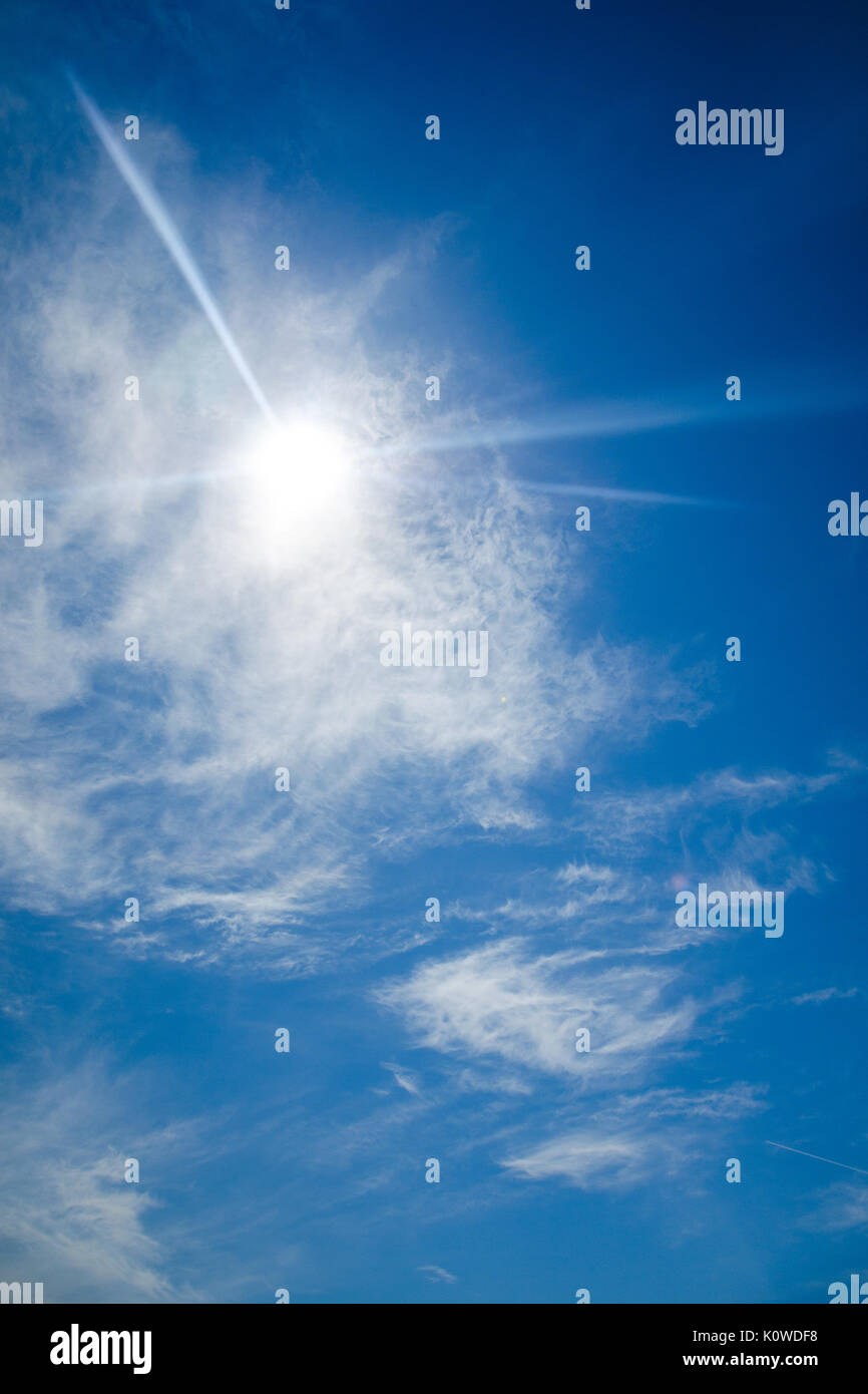 Sun with lens flare, on blue sky background. Glare from the bright sun ...