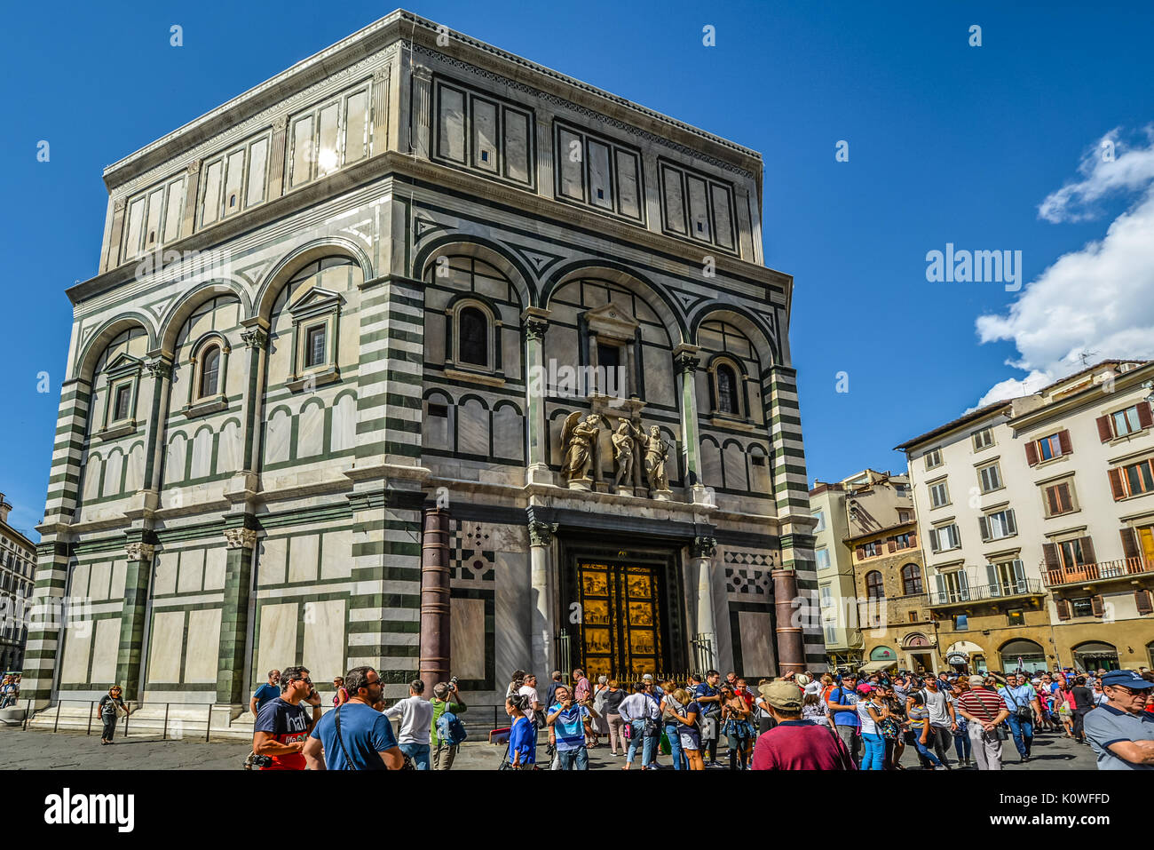 The Florence Baptistery across from the Duomo in Florence Italy showing the bronze doors by Ghiberti as tourists enjoy a sunny day in Tuscany Stock Photo