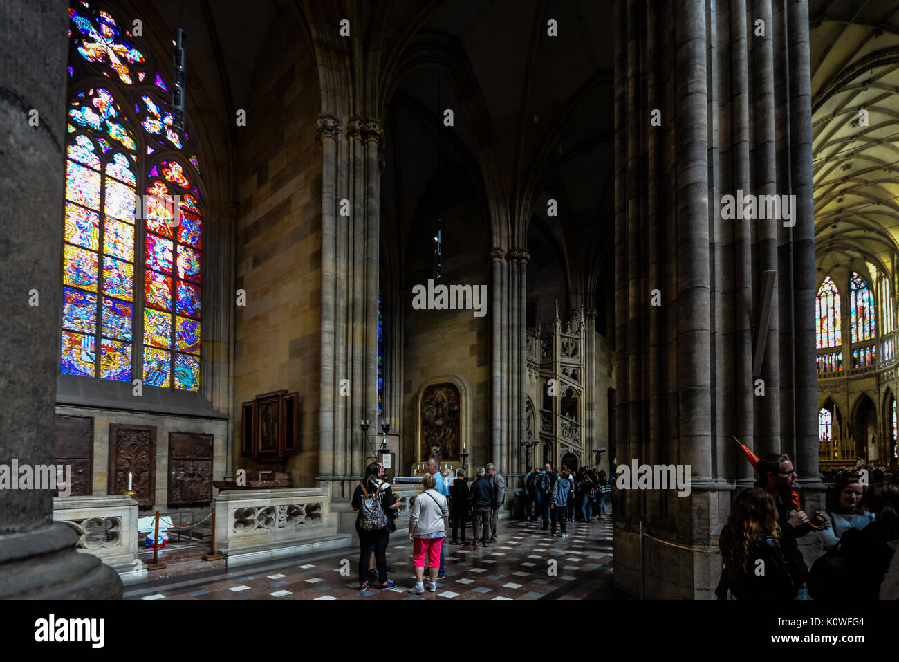 The beautiful gothic interior of St Vitus Cathedral in Prague as tourists and worshipers enjoy the stained glass windows and architecture Stock Photo