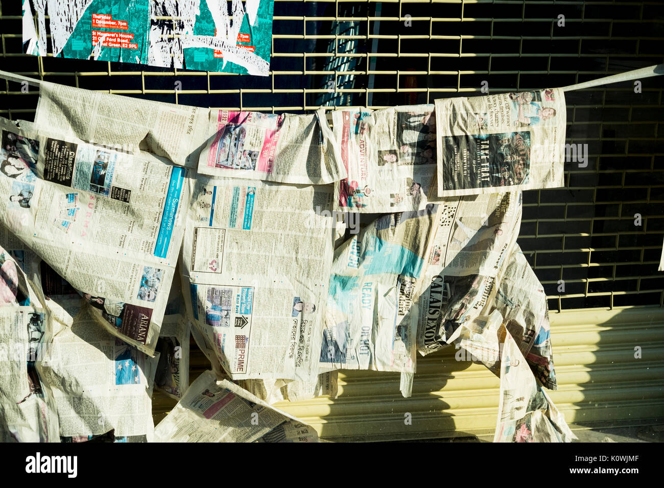 Newspapers hung on a line as if to dry or to hide something within the window in a shop window in East London Stock Photo