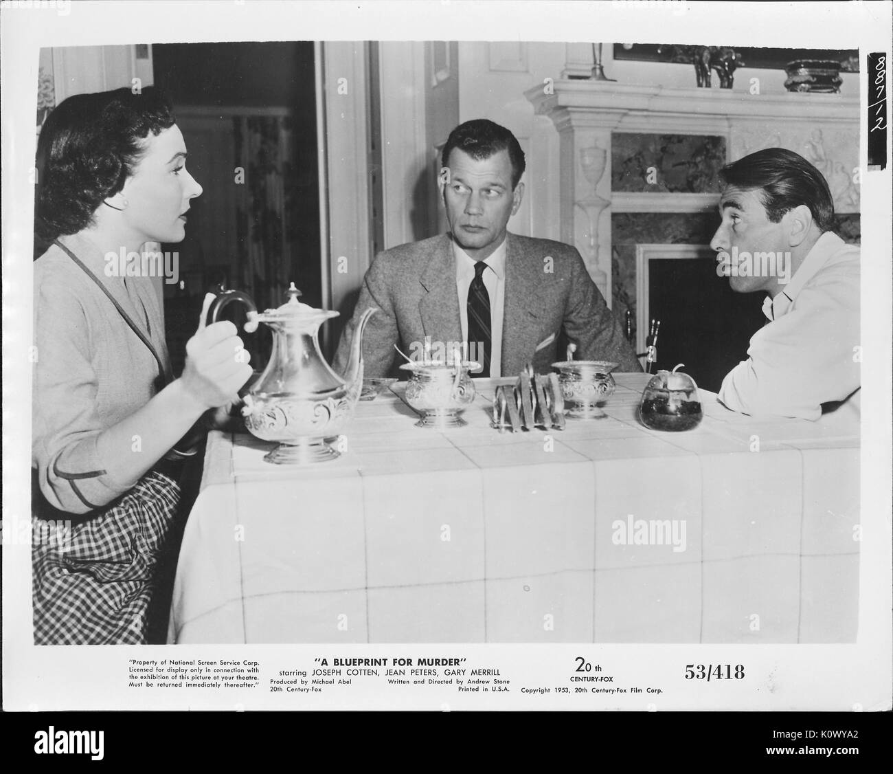 A movie still scene from 'A Blueprint For Murder' (1953 20th Century Fox thriller film), showing three seated people in serious discussion while the woman is holding an elegant tea pot and the two men are intently listening to her, 1953. Stock Photo
