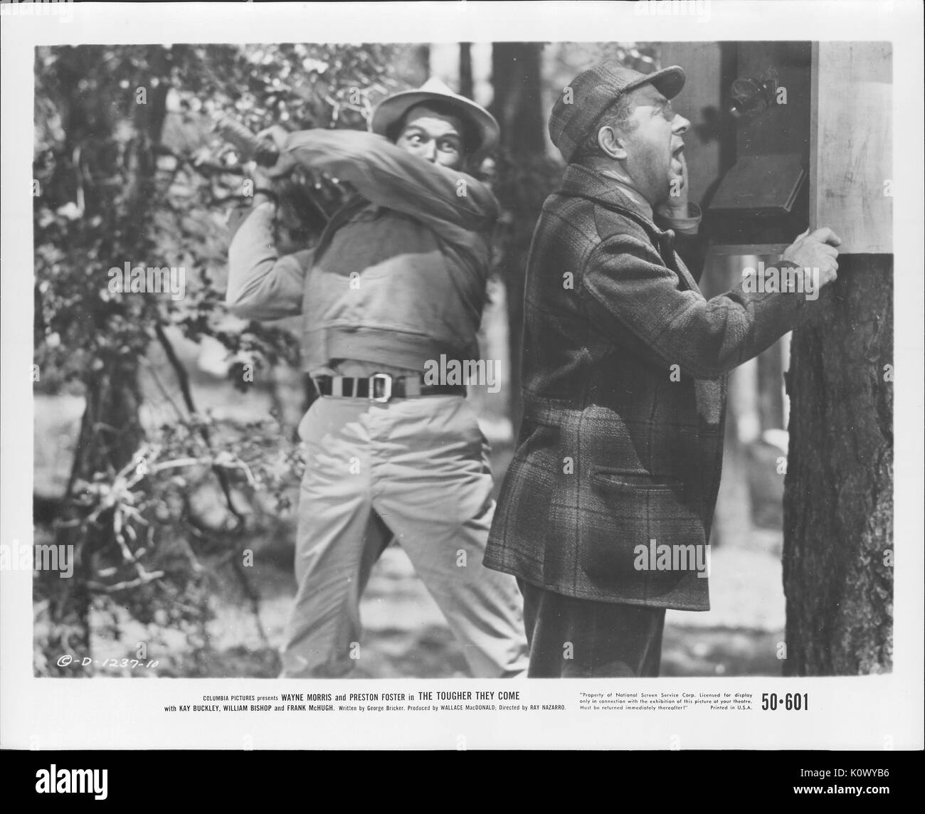 A movie still scene from 'The Tougher They Come' (1950 Columbia Pictures film), showing a man about to clobber another who is making a call on a public phone, 1950. Stock Photo