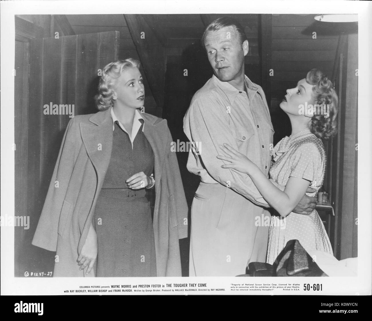 A movie still scene from 'The Tougher They Come' (1950 Columbia Pictures film), showing a young couple holding each other being interrupted by a young blonde woman in a long coat hang over her dress, 1950. Stock Photo