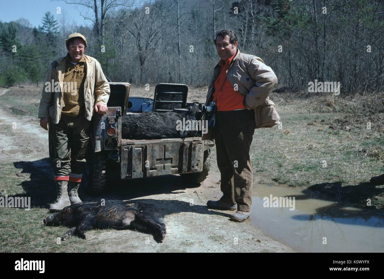 Two hunters standing on a dirt path in the woods, looking proudly at the carcass of a wild boar shot during their hunting trip, Parched Corn Creek, Kentucky, 1975. Photo credit Smith Collection/Gado/Getty Images. Stock Photo