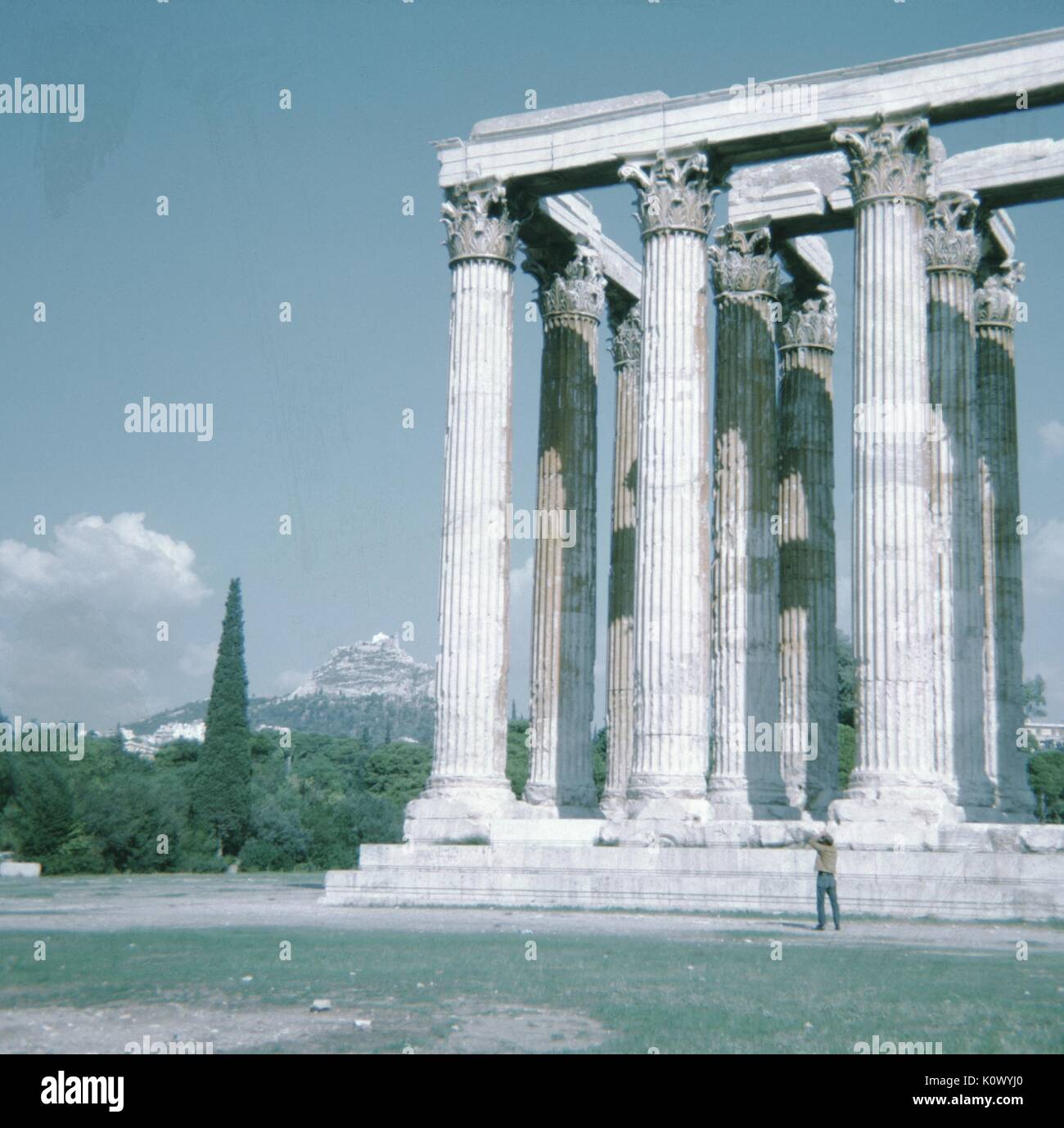 Tourist standing with columns at Greek ruins, pointing towards the