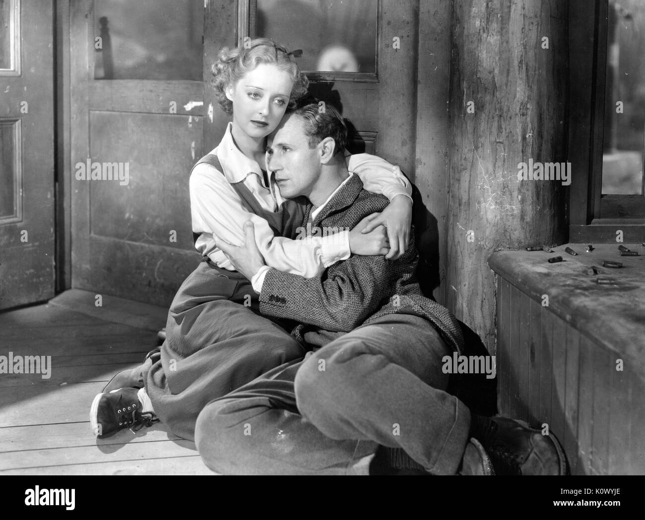 Bette Davis holding a man, lying on the floor of a room, in a movie still, 1949. Photo credit Smith Collection/Gado/Getty Images. Stock Photo
