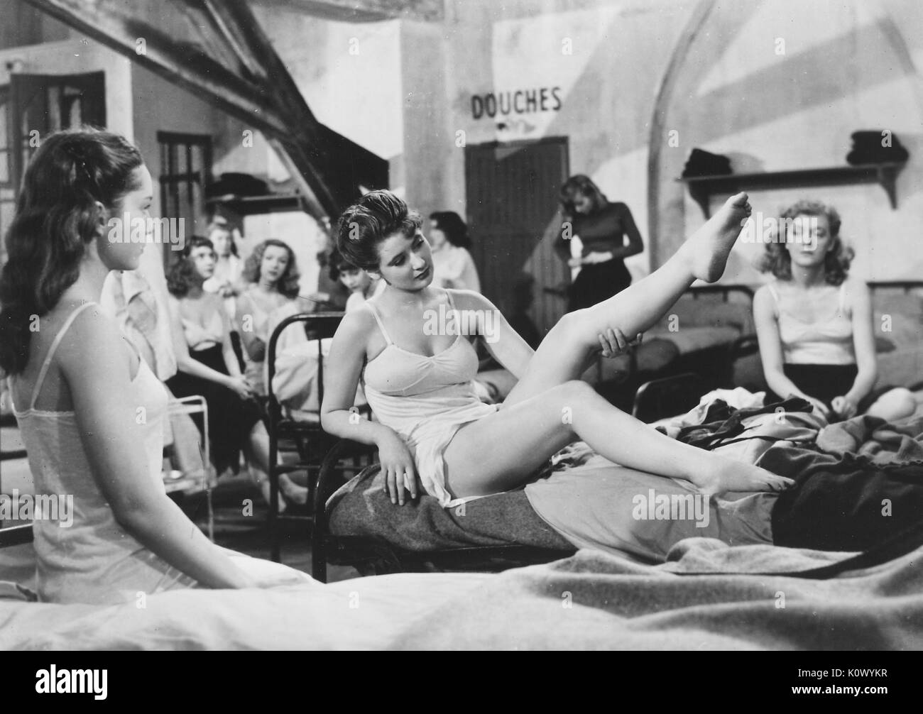 Au Royaume Des Cieux (In the Kingdom of Heaven), movie still of girls sitting on beds in a dormatory, one girl showing off her leg, from the film noir movie by director Julien Duvivier, which tells the story of girls in a female reformatory who are persecuted by a sadistic head warden, and who attempt to escape with the help of the heroines lover, played by Serge Reggiani, 1949. Stock Photo