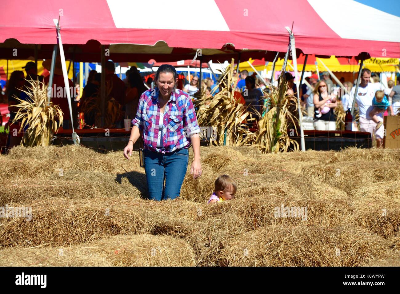 Mother and toddler daughter going through a hay bail maze. Stock Photo