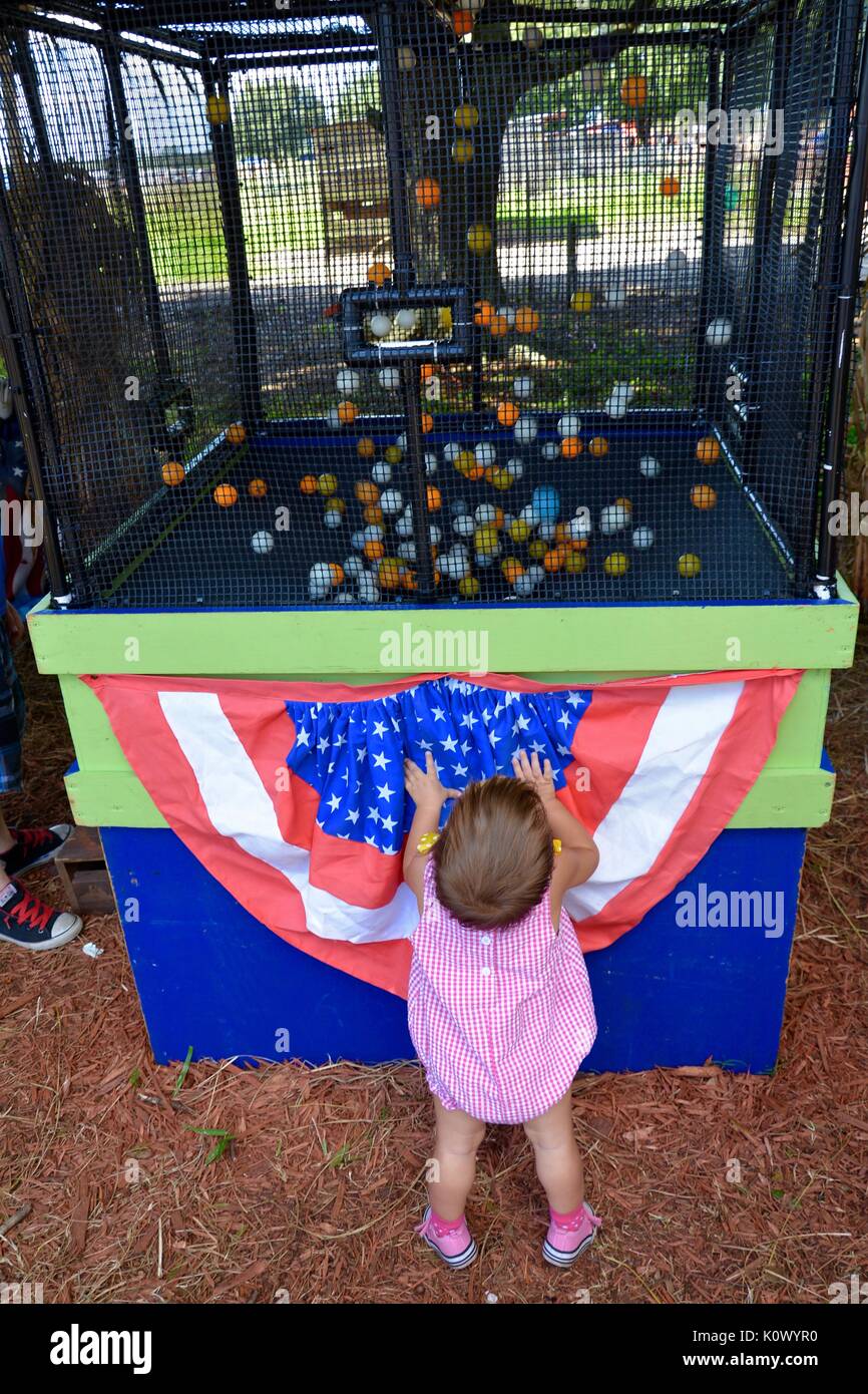 female toddler watching a festival game with a lot of ping pong balls Stock Photo