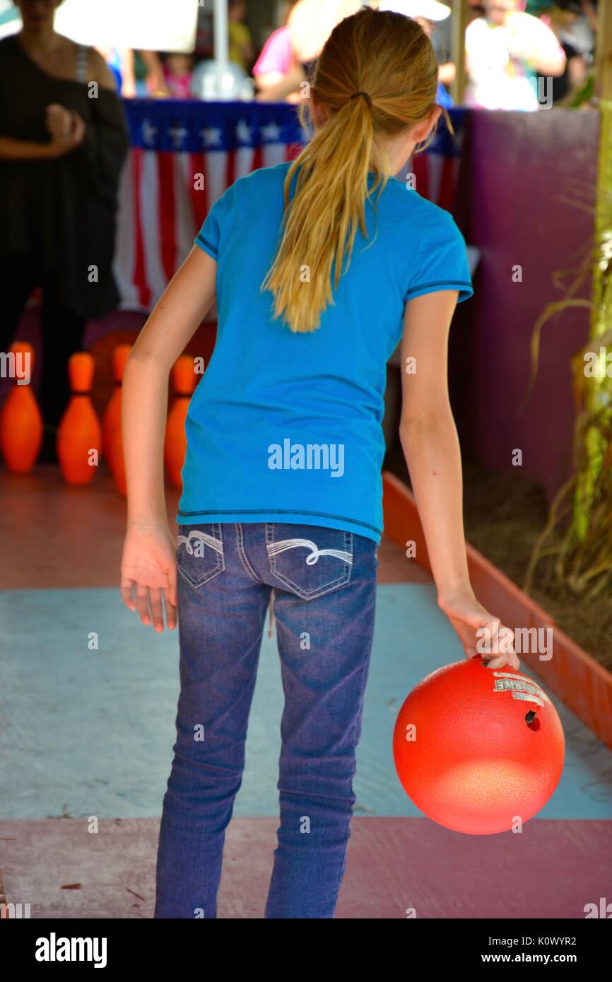 Young girl playing bowling game at a fall festival. Stock Photo