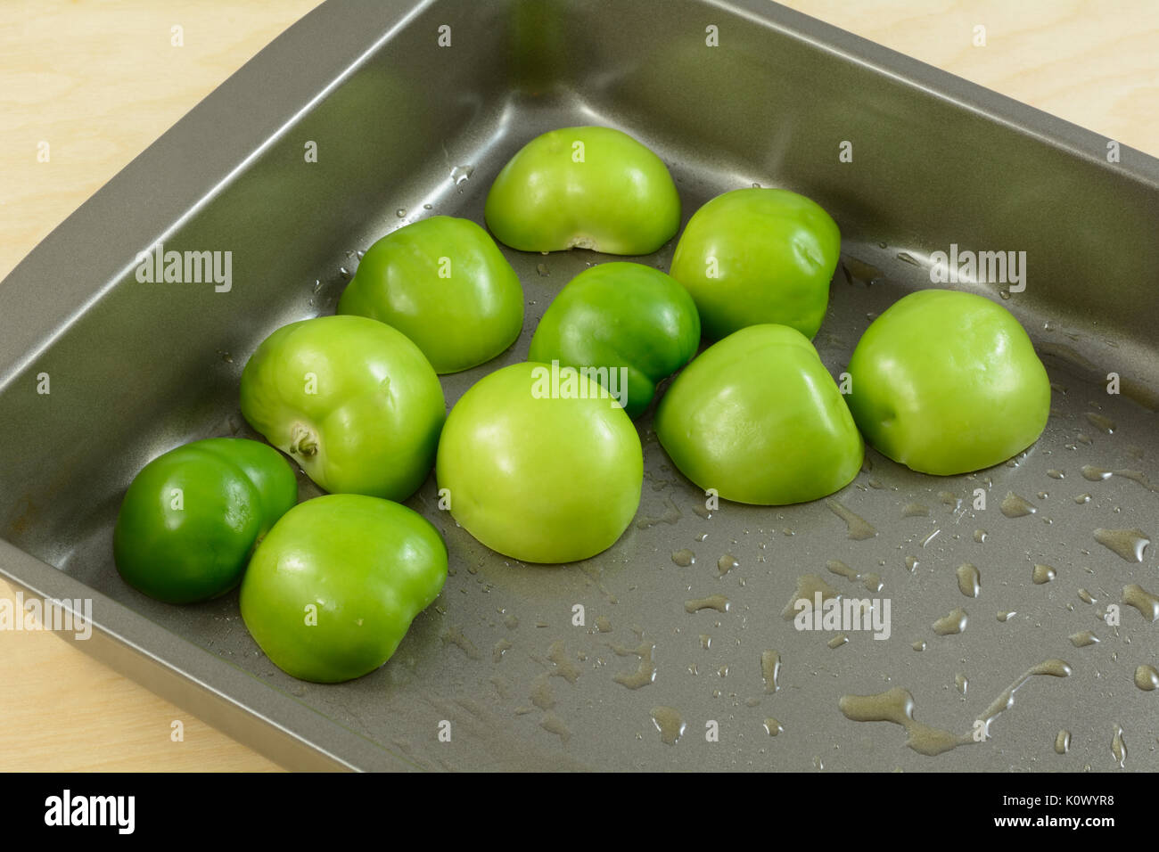 Raw tomatillo halves in baking pan with olive oil Stock Photo
