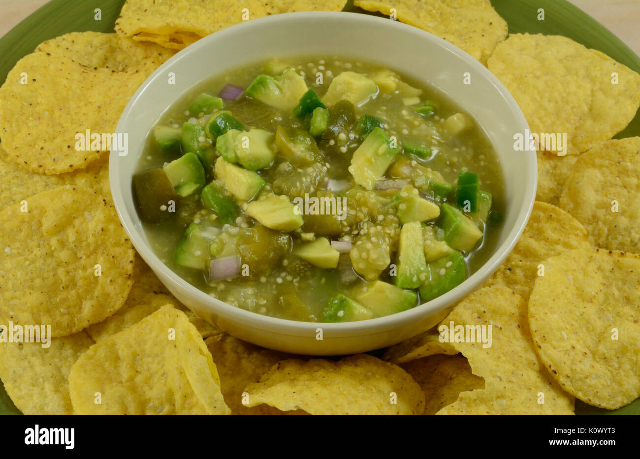 Close up of avocado and tomatillo salsa verde guacamole mixture with round tortillas chips on plate Stock Photo